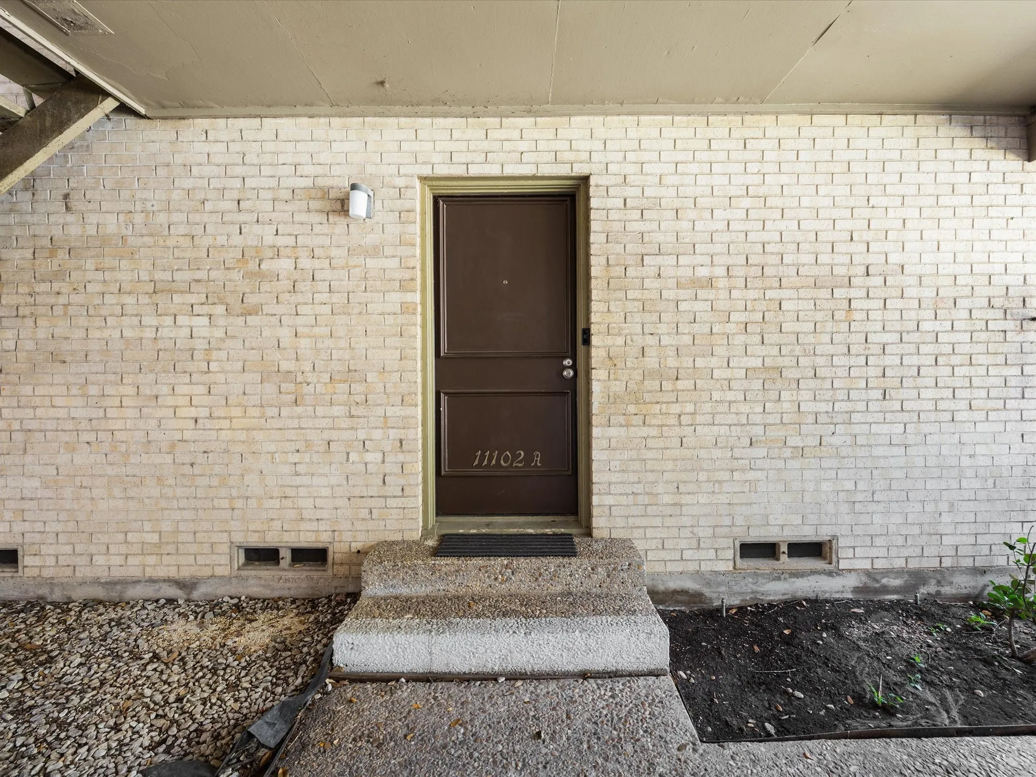 View of exterior entry with crawl space and brick siding