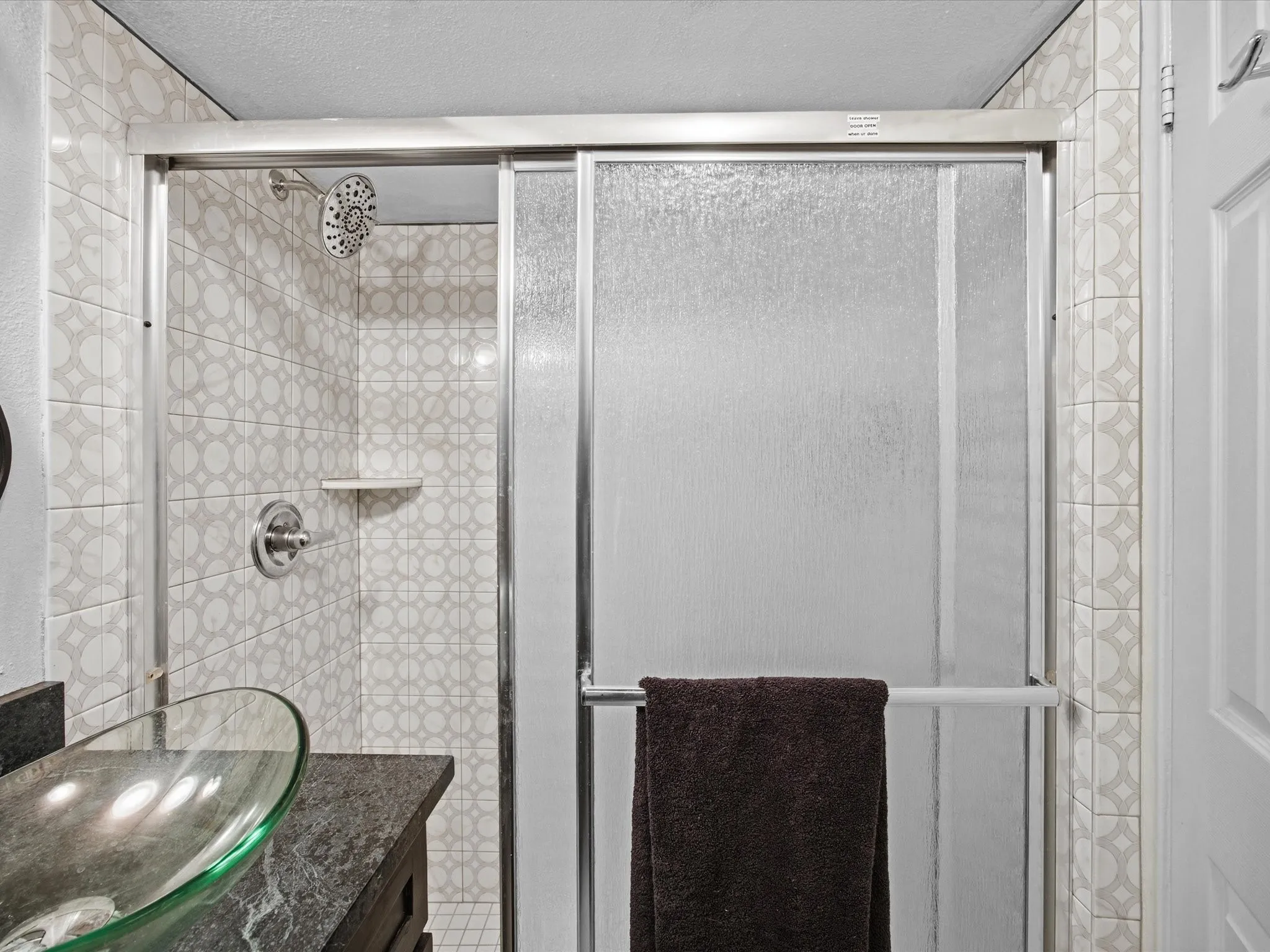 Primary bathroom with vanity, a shower stall, and a textured ceiling