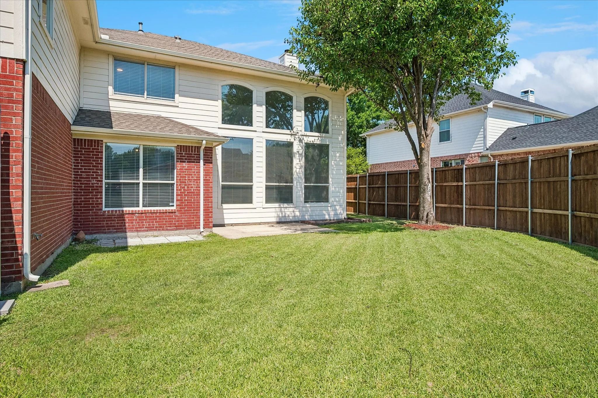 Expansive backyard featuring a lush lawn and a concrete patio