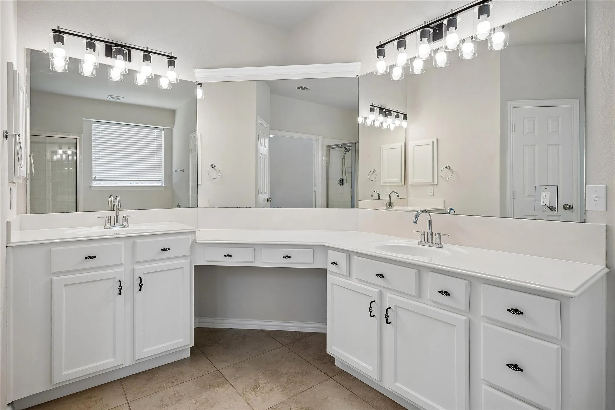 Spacious bathroom featuring a dual vanity with white cabinetry, a built-in makeup counter, and a large wall-mounted mirror