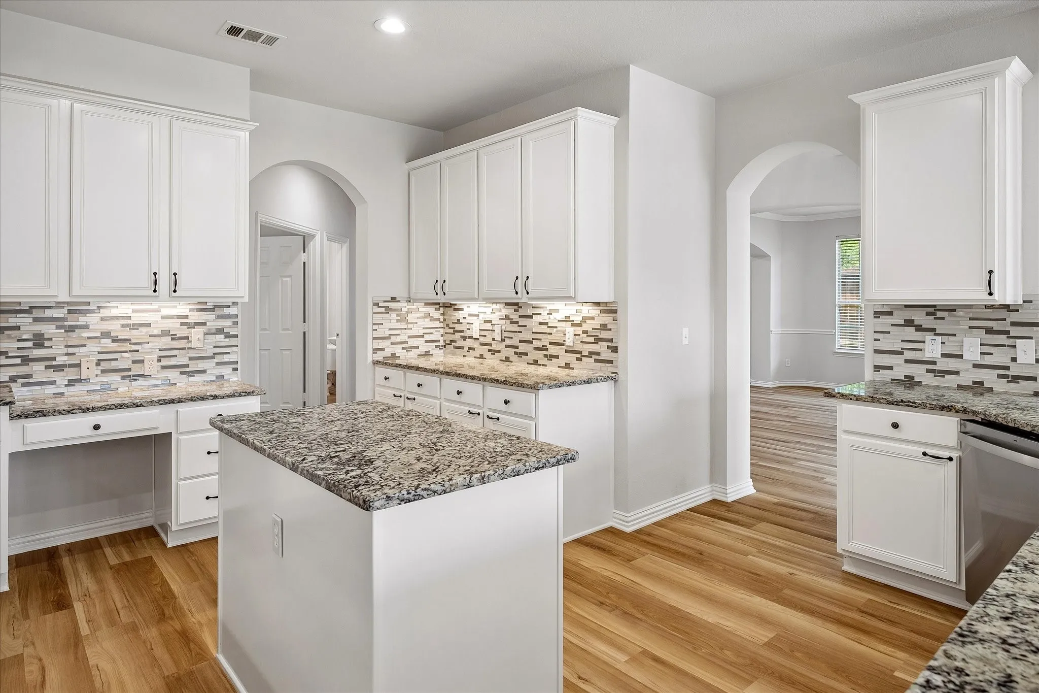 Kitchen featuring white cabinetry, granite countertops, a mosaic tile backsplash, and wood-finish flooring