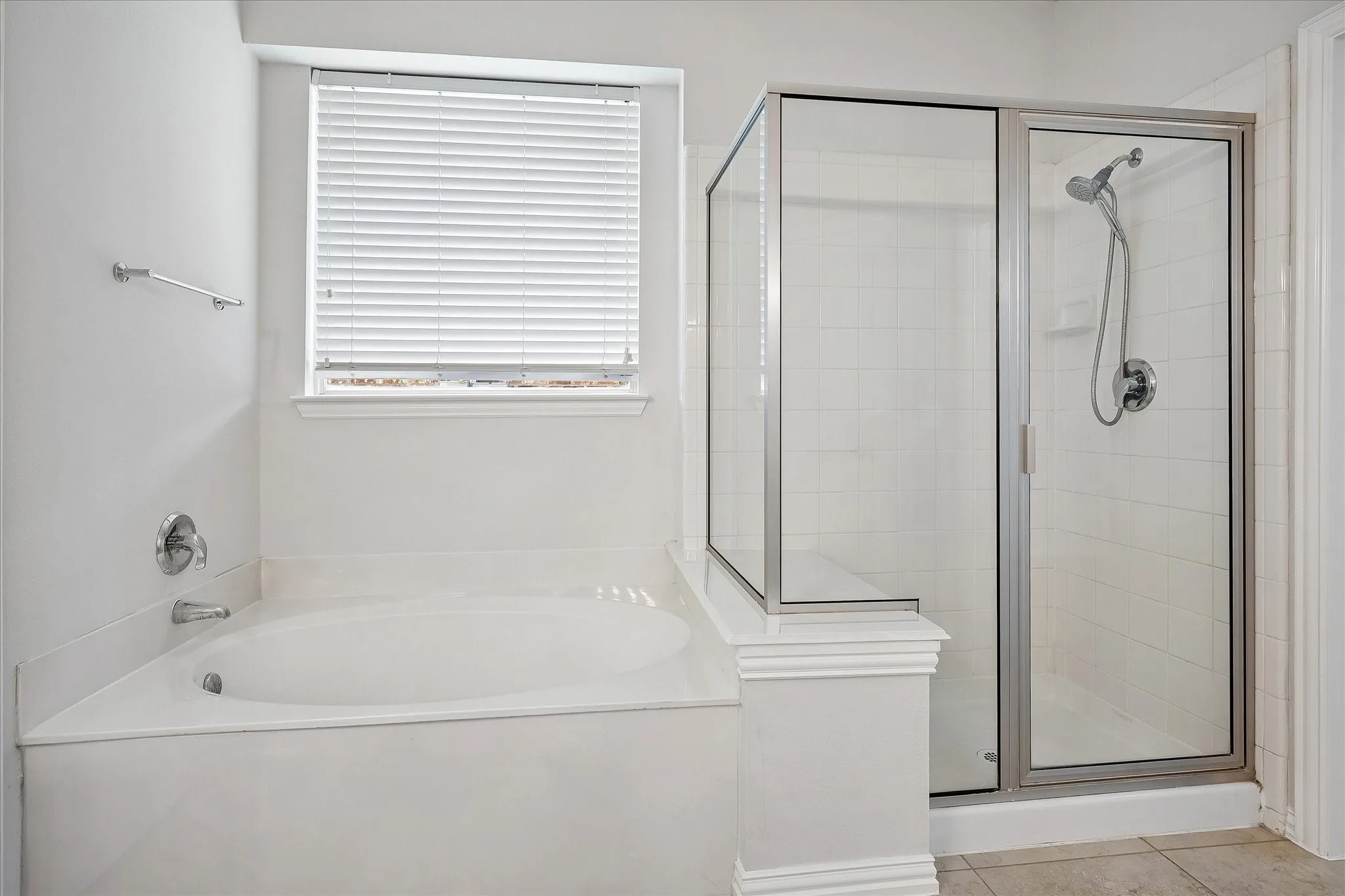 Soaking tub with a tiled surround, chrome fixtures, and privacy blinds