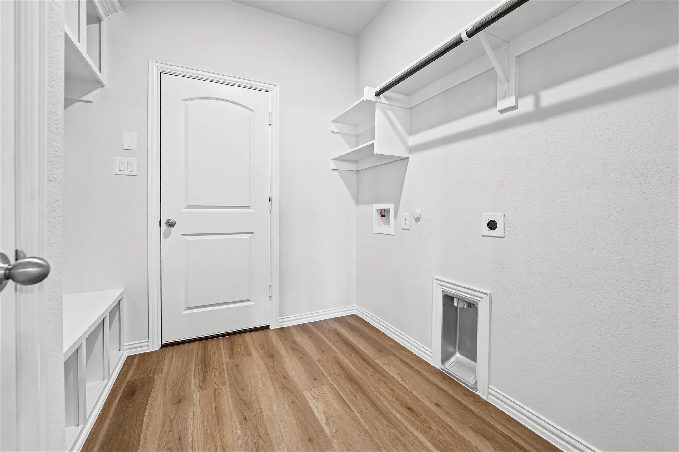 Utility room with wood-finish flooring, built-in shelving, and a hanging rod