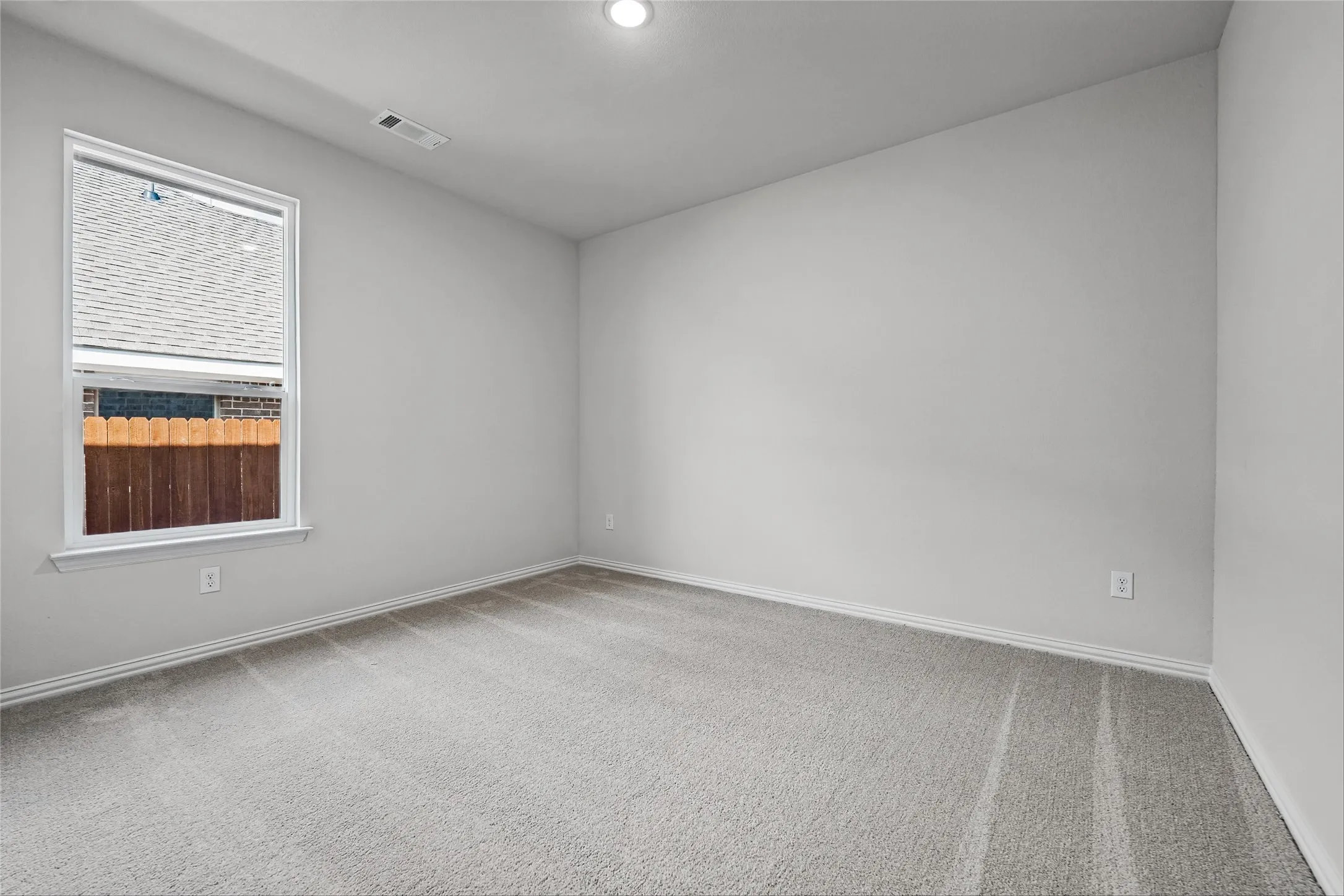 Spacious room featuring neutral carpeting, a large window, and recessed lighting
