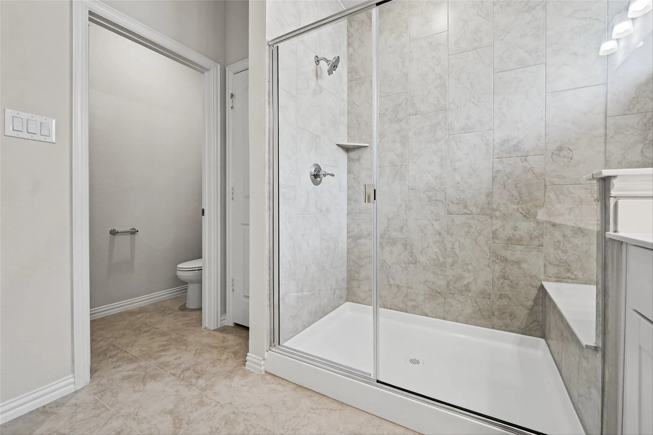 Walk-in shower with clear glass enclosure, tiled walls, and an integrated shower bench