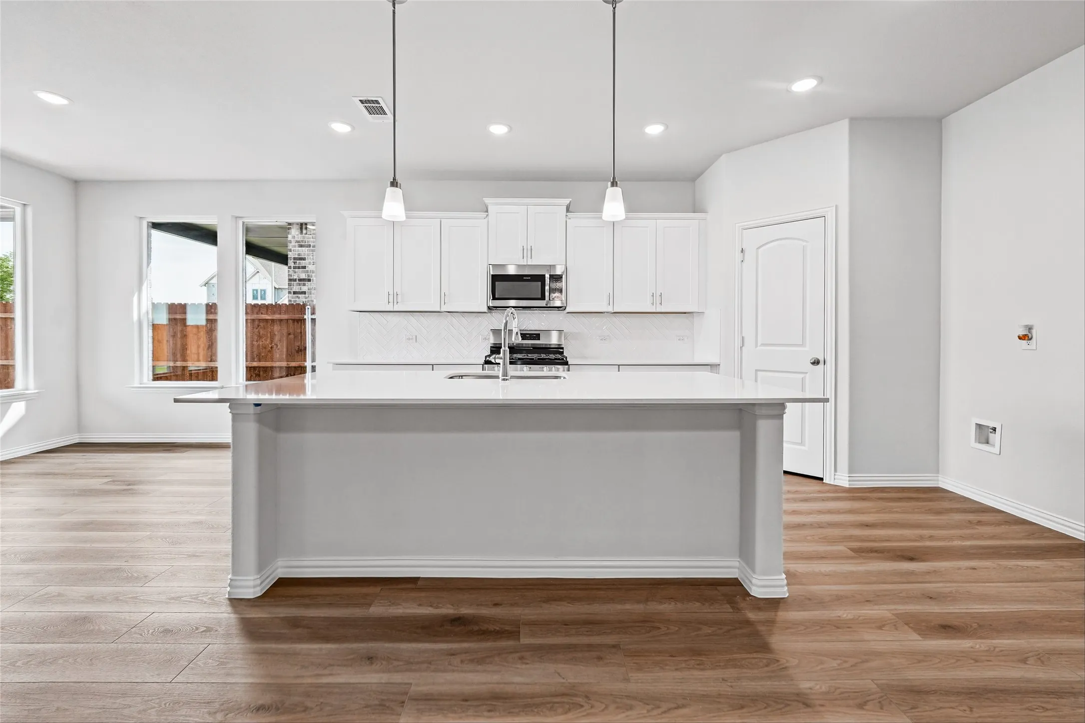 Kitchen with a center island, white cabinetry, integrated stainless steel appliances, and wood-finish flooring