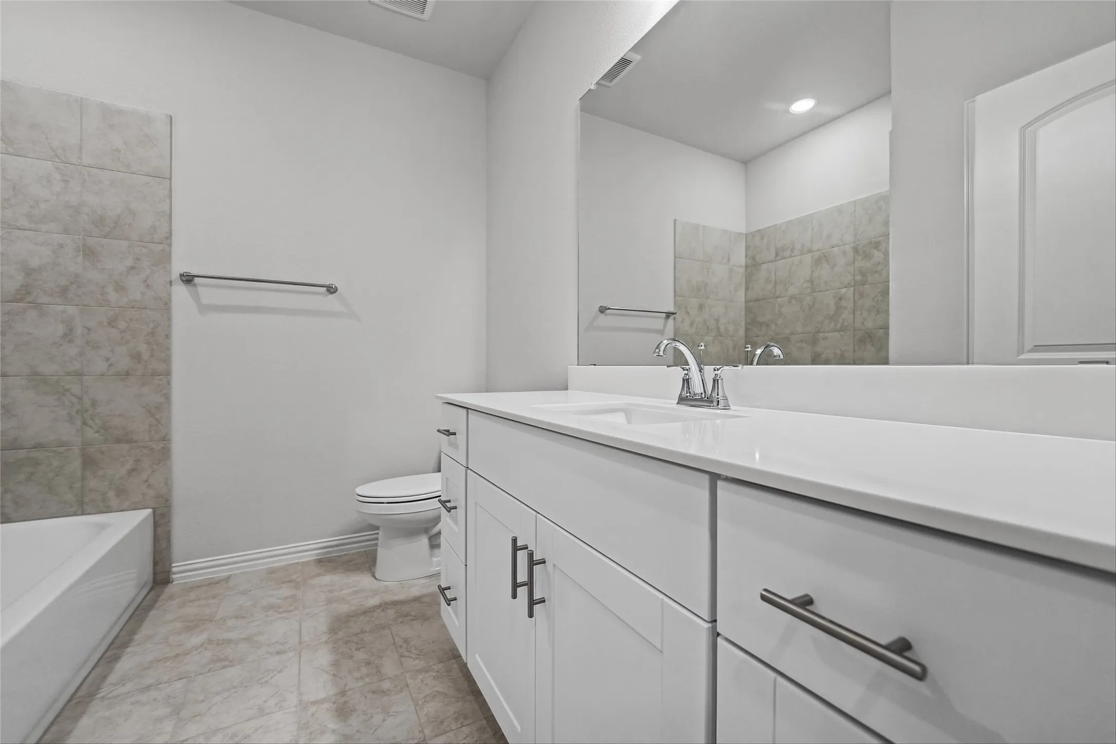 White vanity with an integrated sink, polished chrome faucet, and gray tile flooring