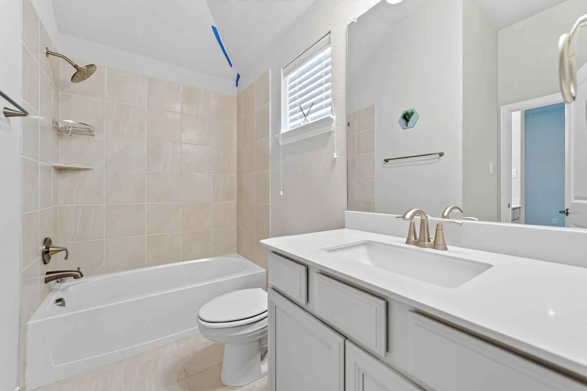 Bathroom featuring a tub/shower combination with light-toned tiled surround and a built-in shelf