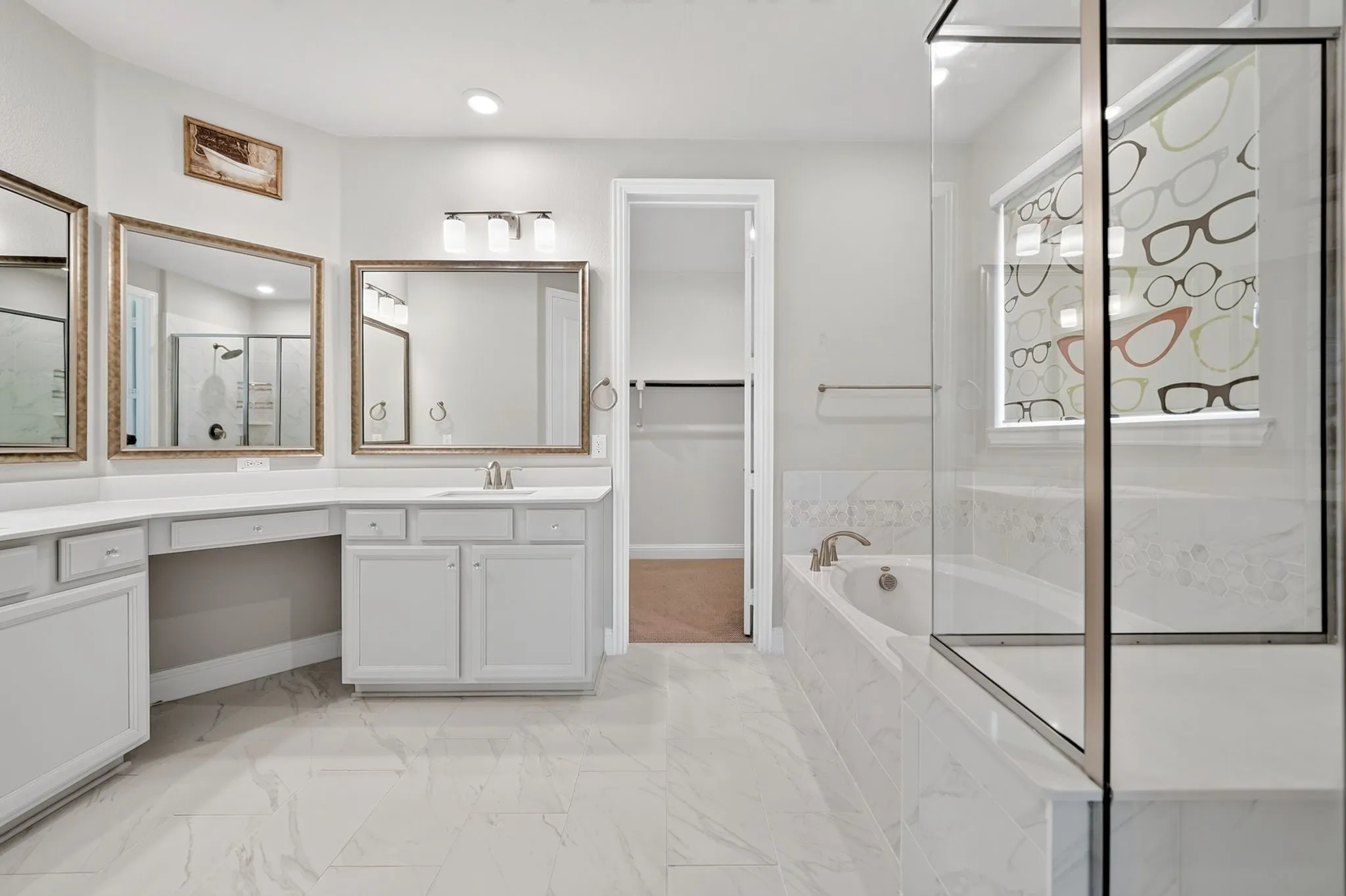 Spacious bathroom featuring a double vanity with ample counter space, a built-in makeup vanity, a soaking tub, a separate glass-enclosed shower, and large format tile flooring