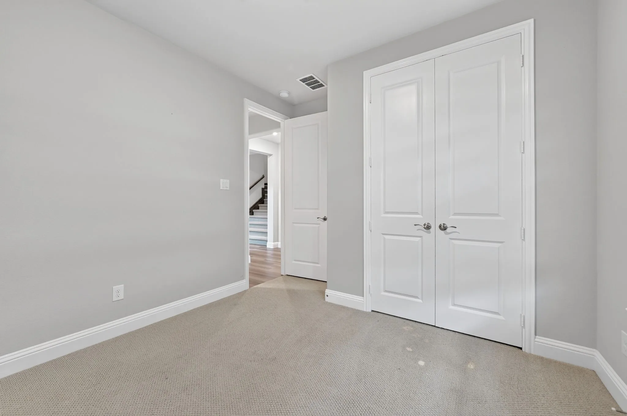 Carpeted room featuring light gray walls, white baseboards, and two-panel interior doors