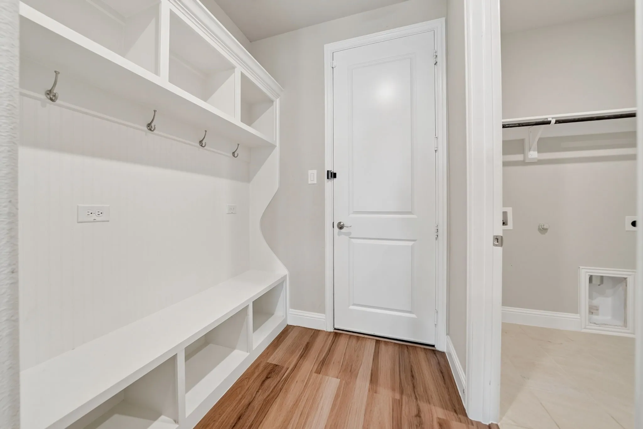 Built-in white storage unit featuring shelving and coat hooks
