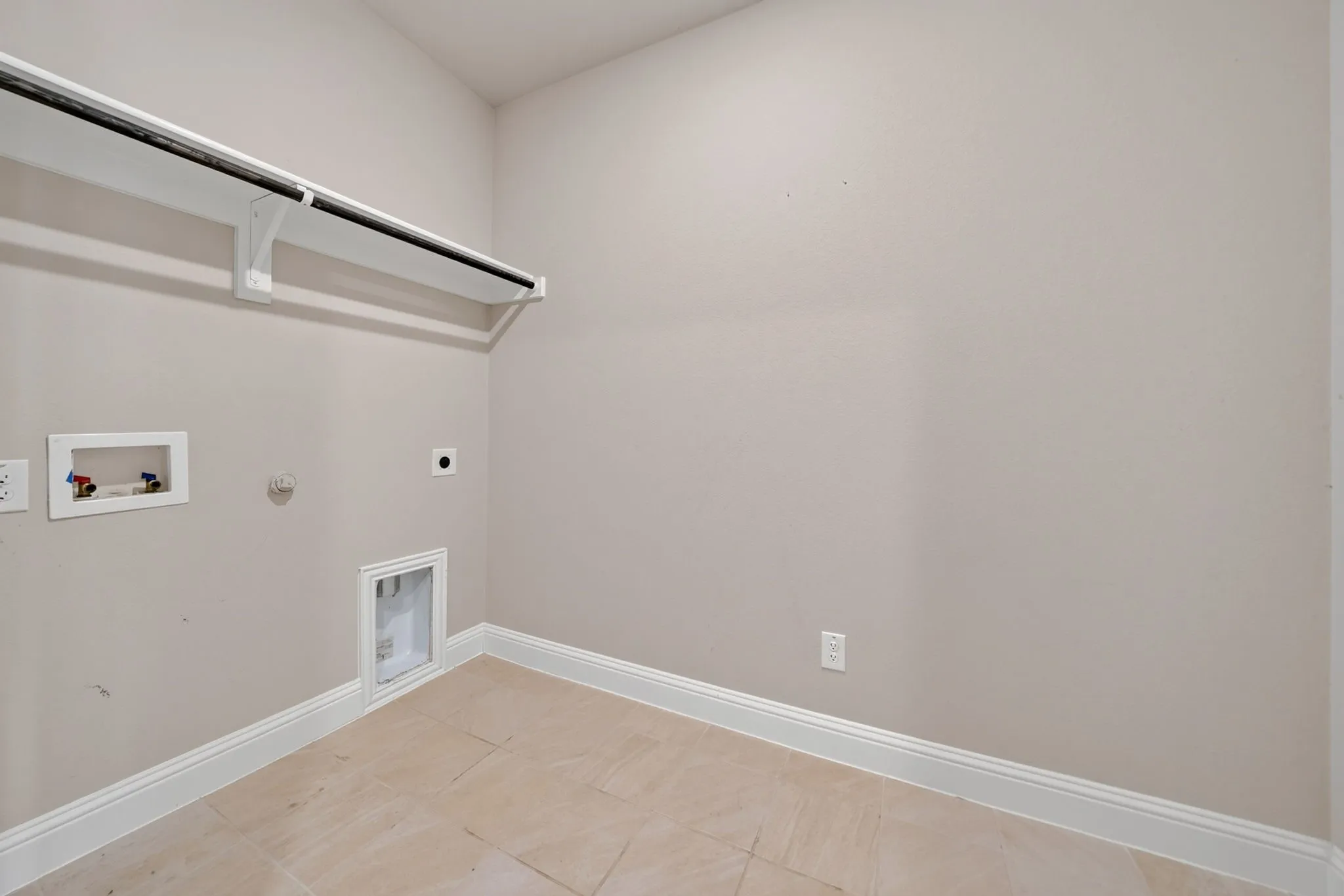 Laundry room featuring a neutral wall color, tile flooring, white baseboards, and a built-in shelf with a hanging rod