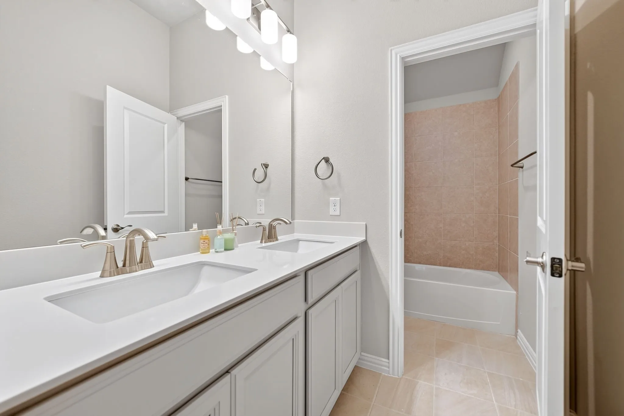 Bathroom featuring a double vanity with integrated sinks, brushed nickel fixtures, and a spacious mirror