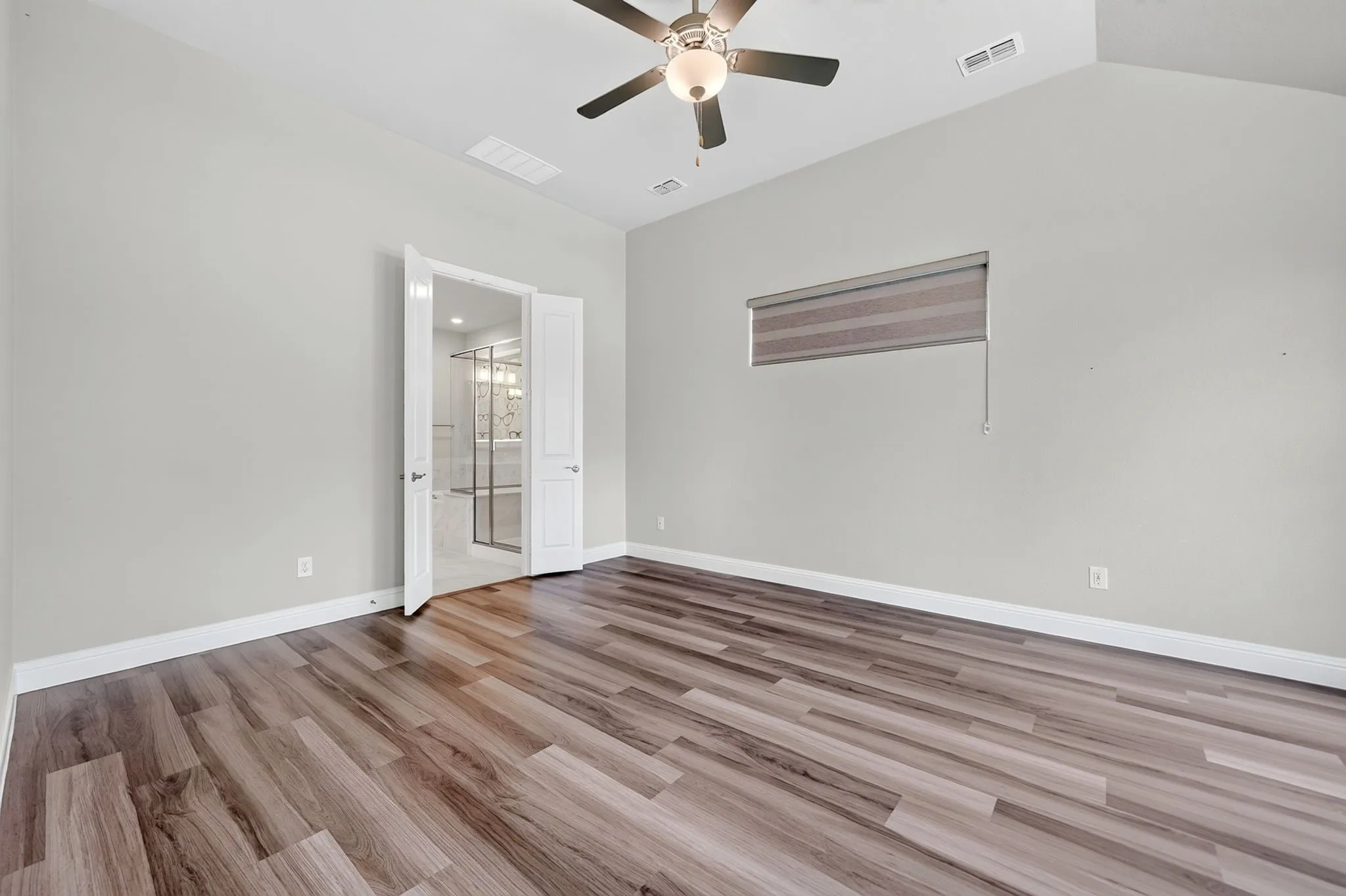 Spacious interior featuring vaulted ceilings, wood-finish flooring, and a ceiling fan with integrated lighting