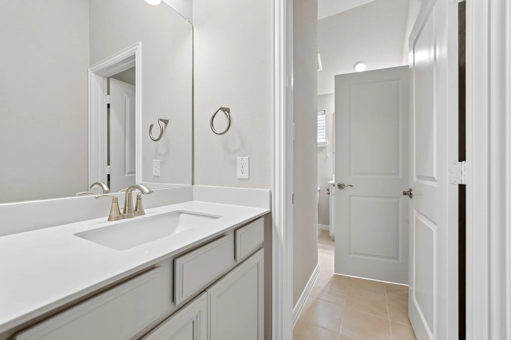 Modern vanity featuring an integrated rectangular sink, light-toned countertop, and brushed nickel faucet