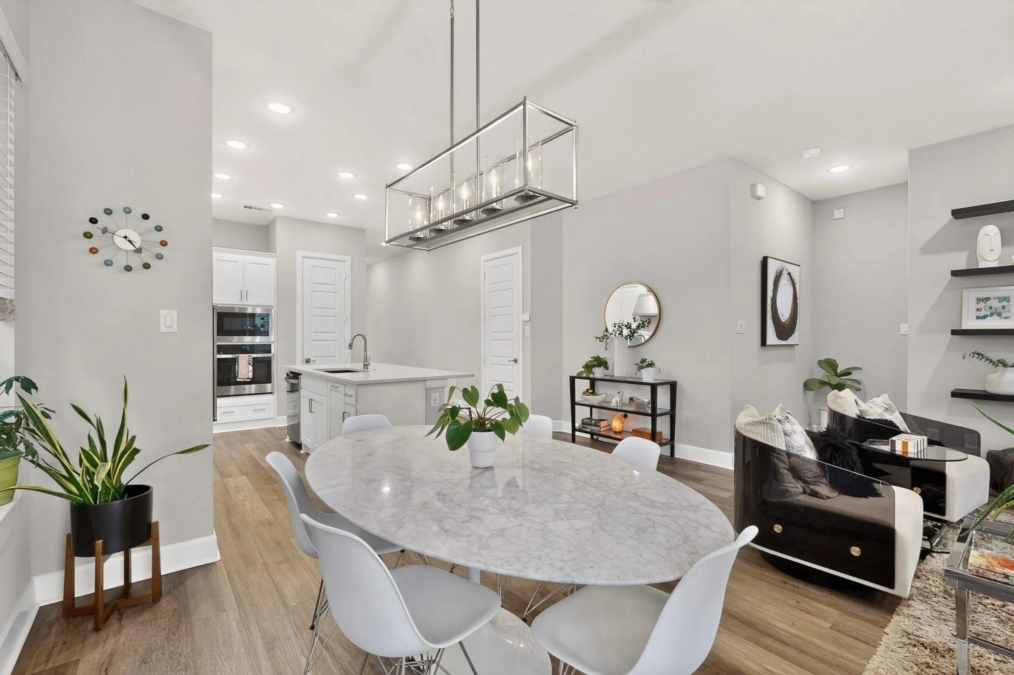 Open-concept dining and living area featuring wood-finish flooring, recessed lighting, and a linear chandelier