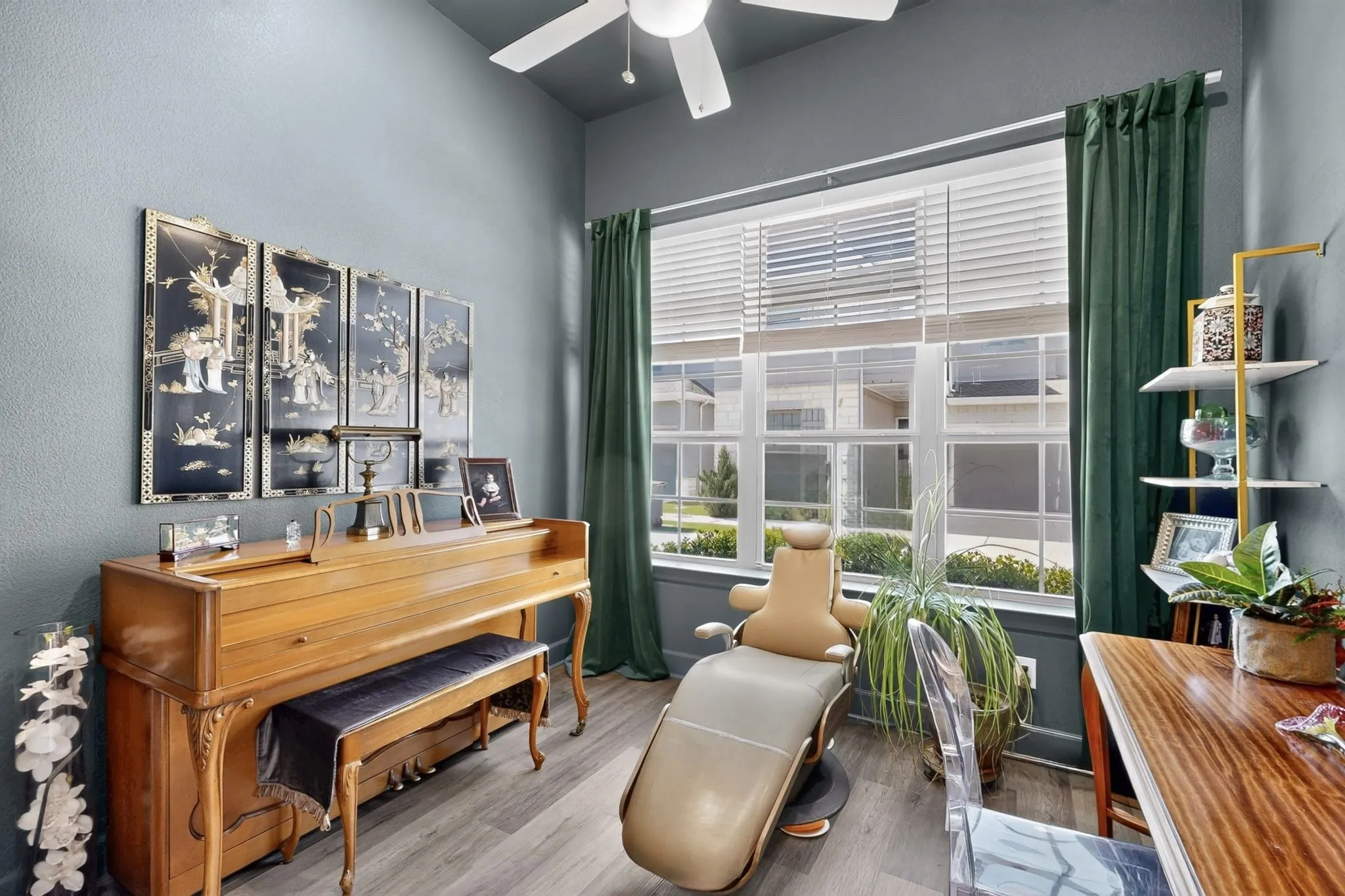 Room featuring wood-finish flooring, a contemporary ceiling fan, and a large window with white blinds and green drapes