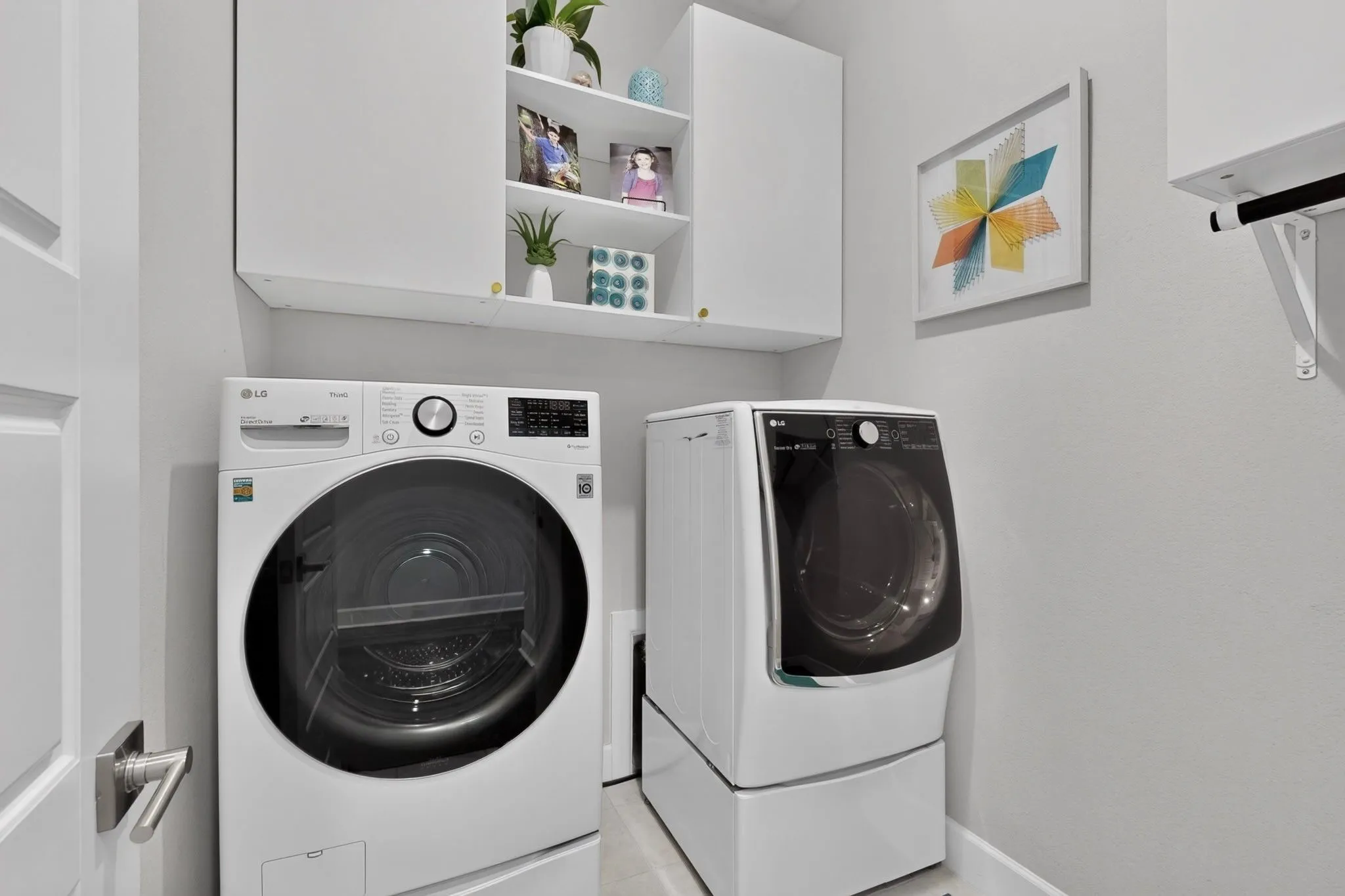 Dedicated laundry area featuring white upper cabinetry, open shelving, and light gray wall paint