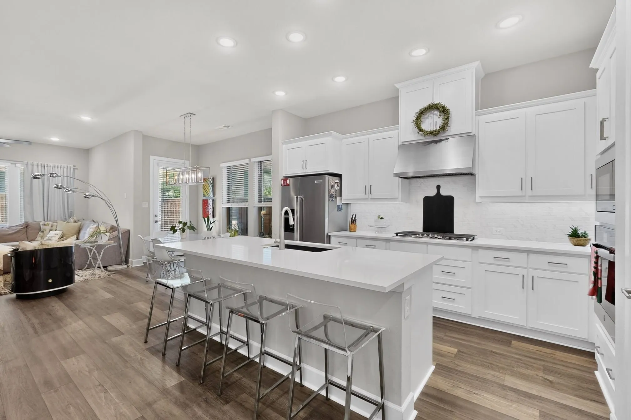 Gourmet kitchen featuring white shaker cabinetry, stainless steel appliances, a large center island with counter seating, and wood-finish flooring