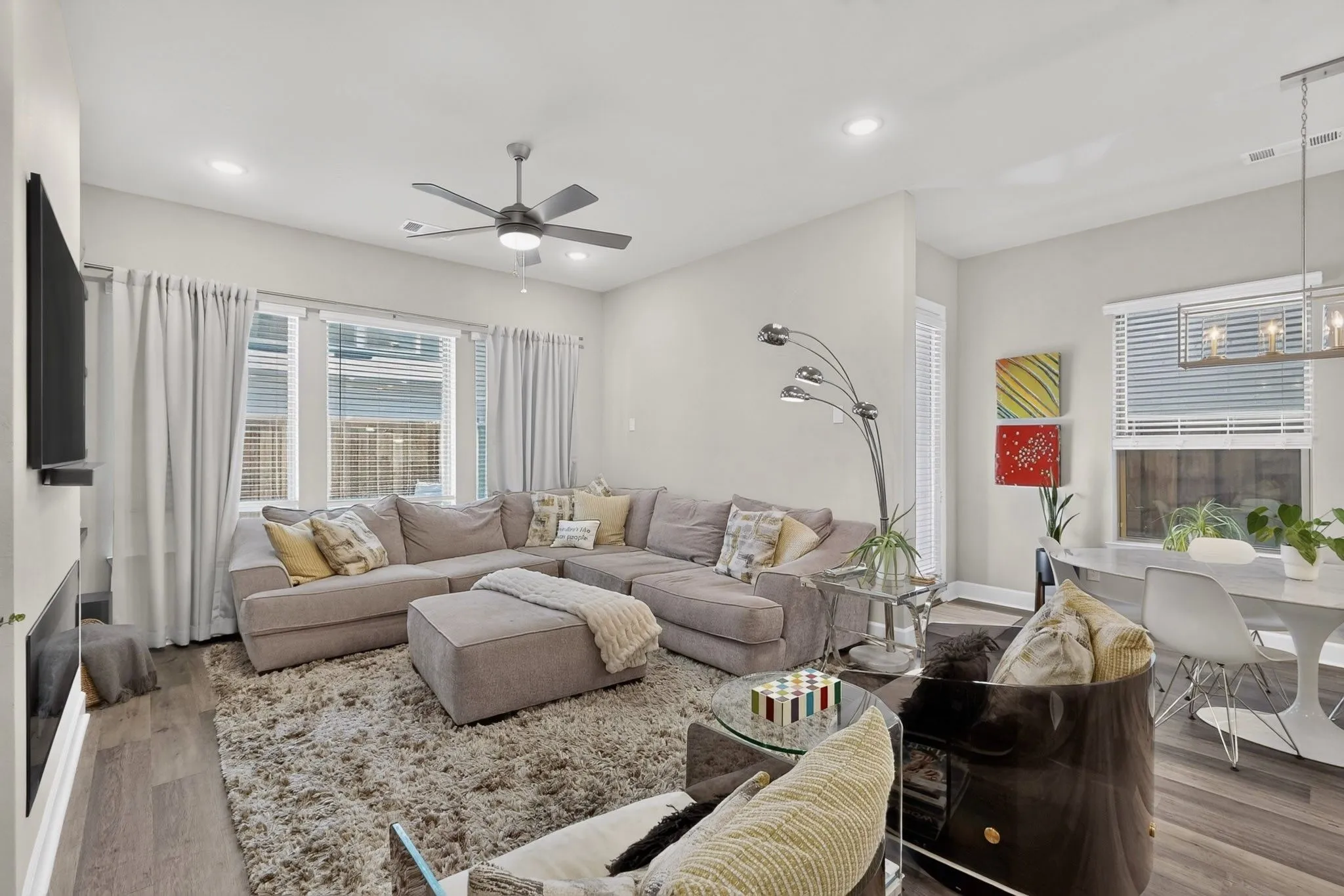 Open-concept living area with wood-finish flooring, a contemporary ceiling fan, recessed lighting, and a built-in linear fireplace
