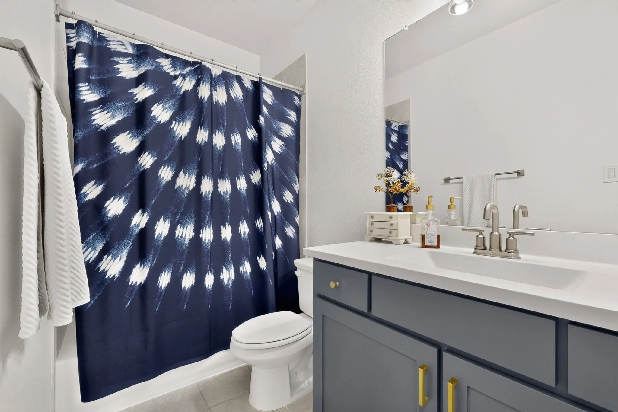 Bathroom featuring a single vanity with a white countertop and undermount sink, brushed nickel faucet, and a large unframed mirror