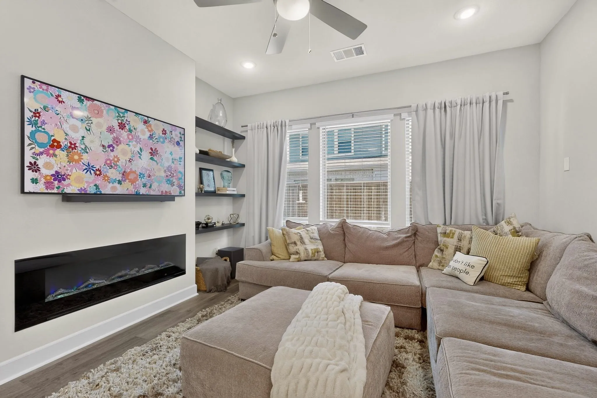 Living area with wood-finish flooring and a contemporary linear electric fireplace