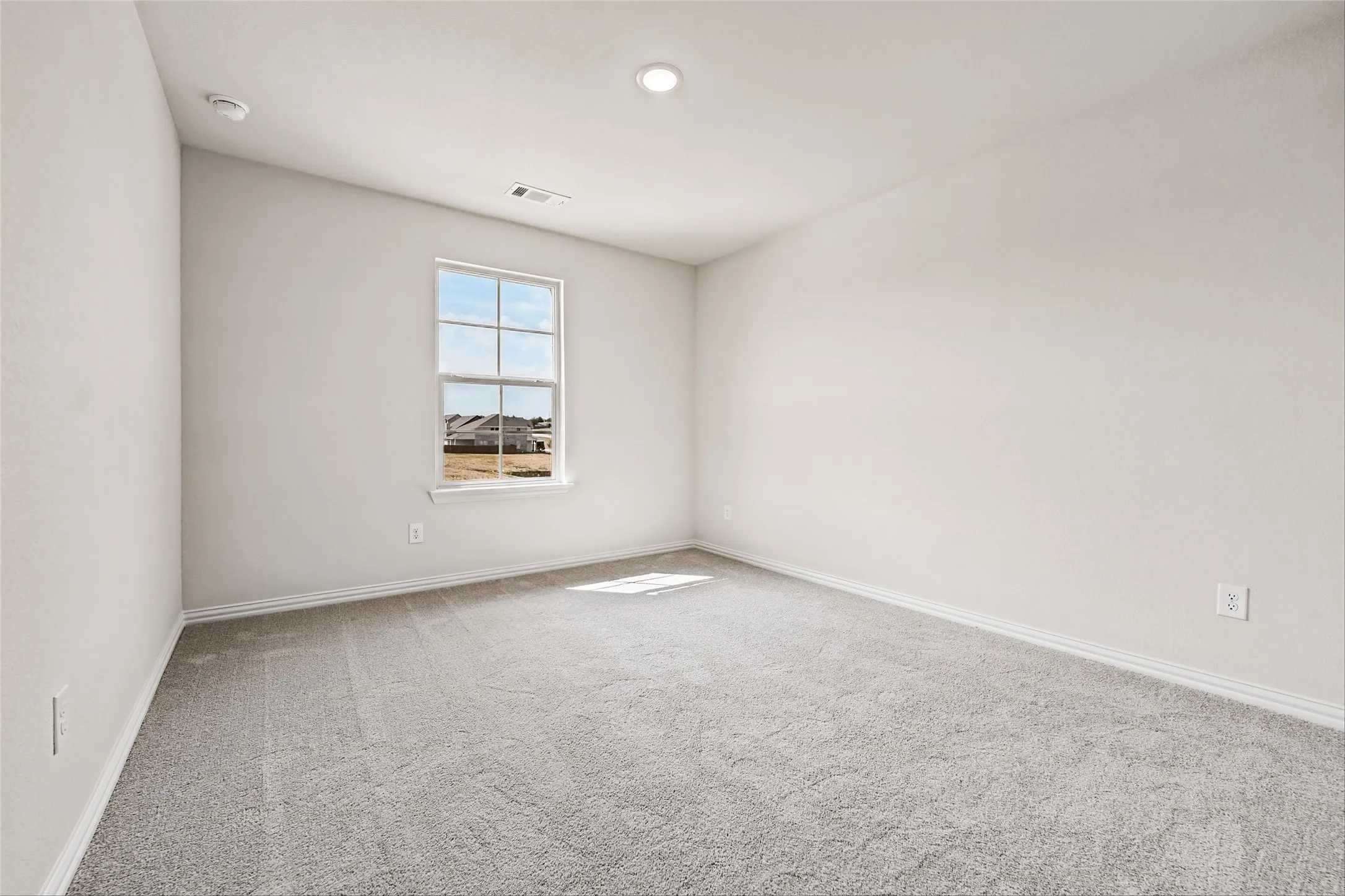 Recessed lighting, light gray carpeting, and a window with a white frame