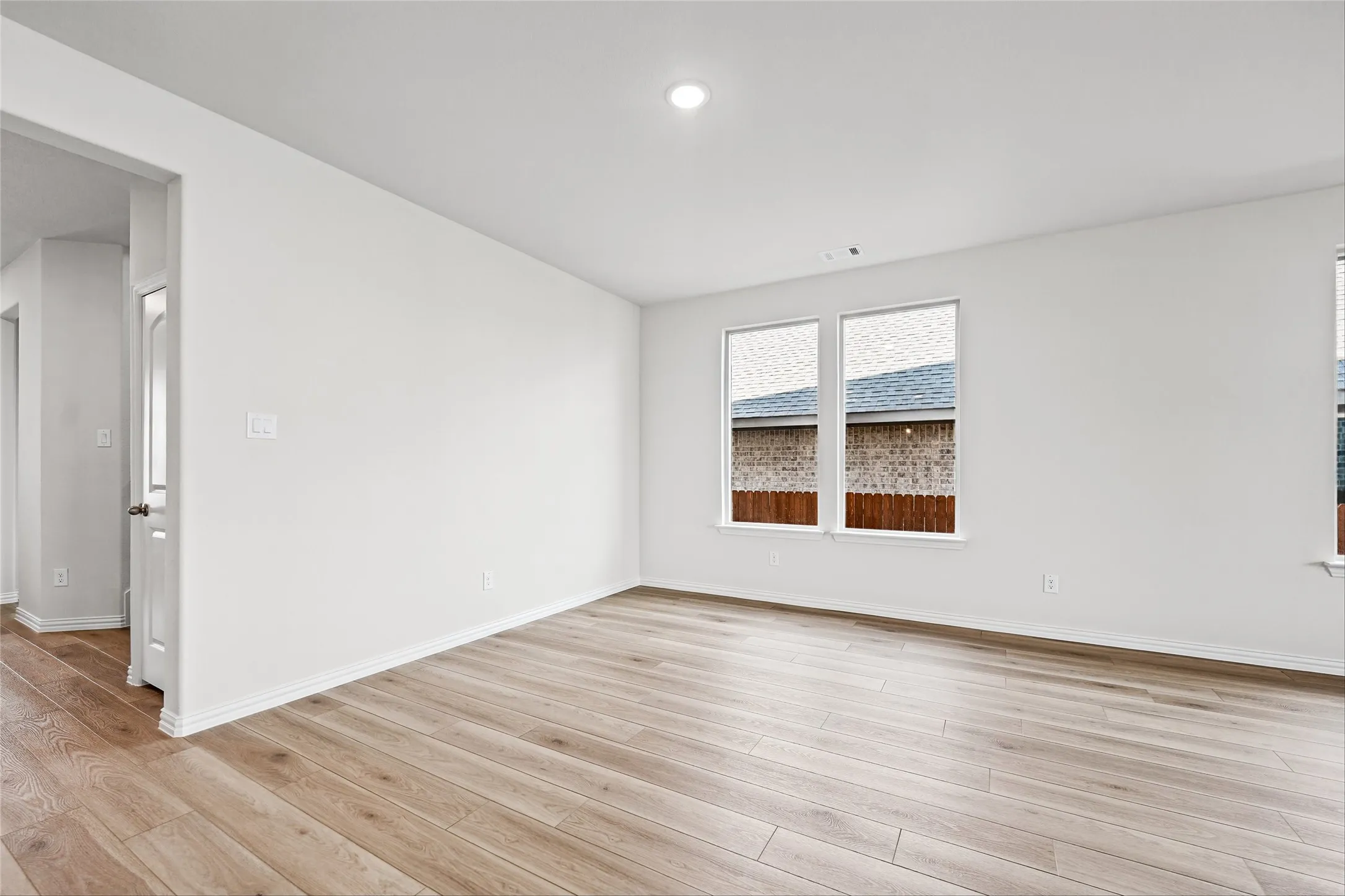 Wood-finish flooring, white walls, recessed lighting, and dual windows