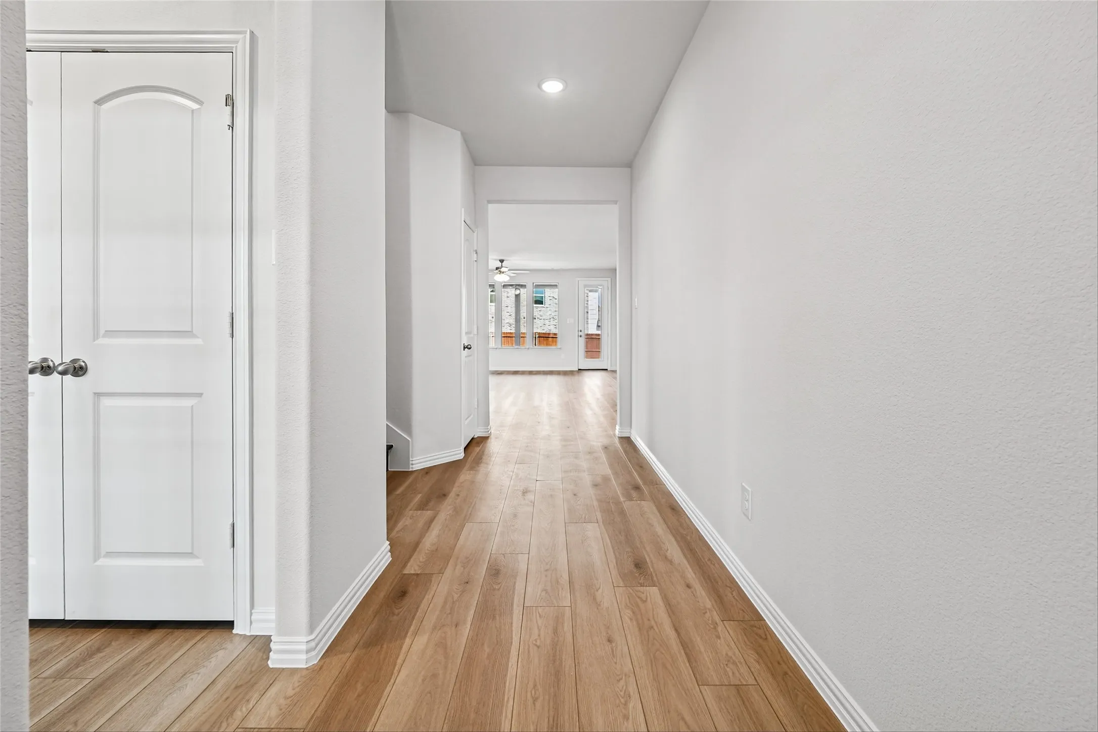 Recessed lighting, wood-finish flooring, white paneled door, and neutral wall finish
