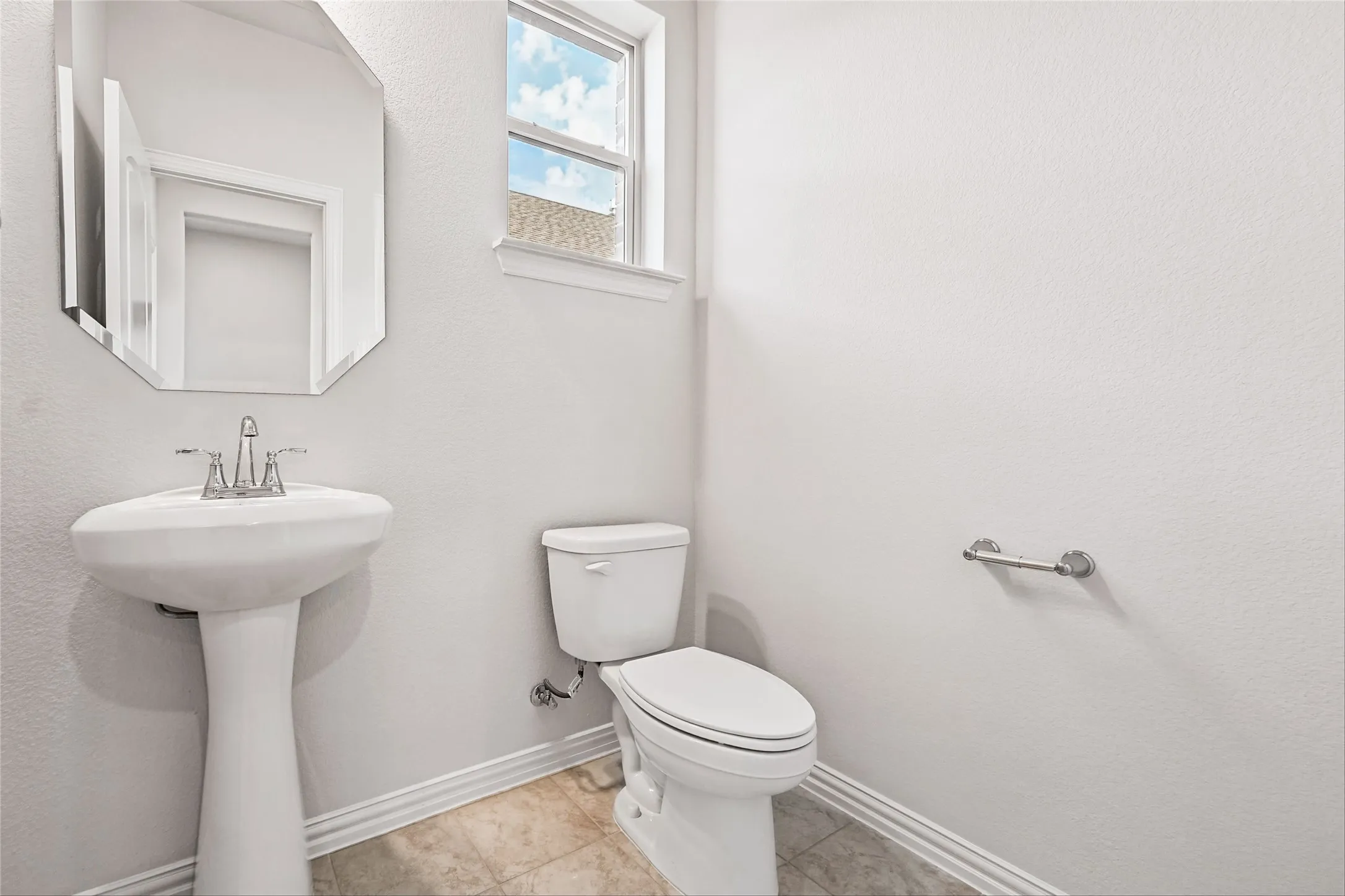 Pedestal sink with chrome faucet, octagonal wall mirror, and window with trim