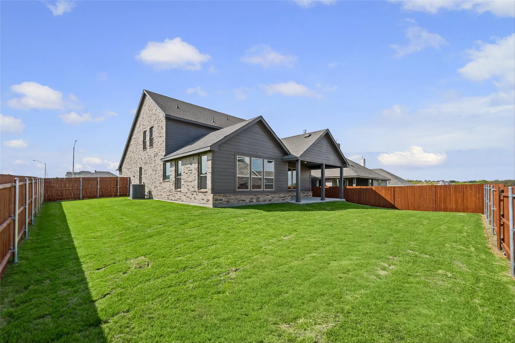 Expansive fenced backyard featuring a substantial lawn