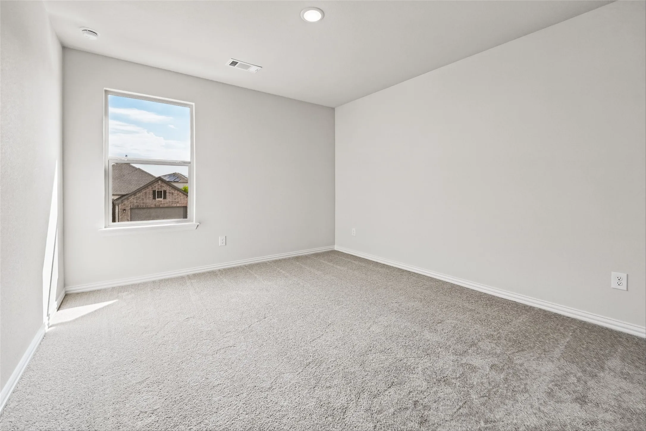 Neutral-toned carpeting, single pane window, recessed ceiling lighting, and white trim