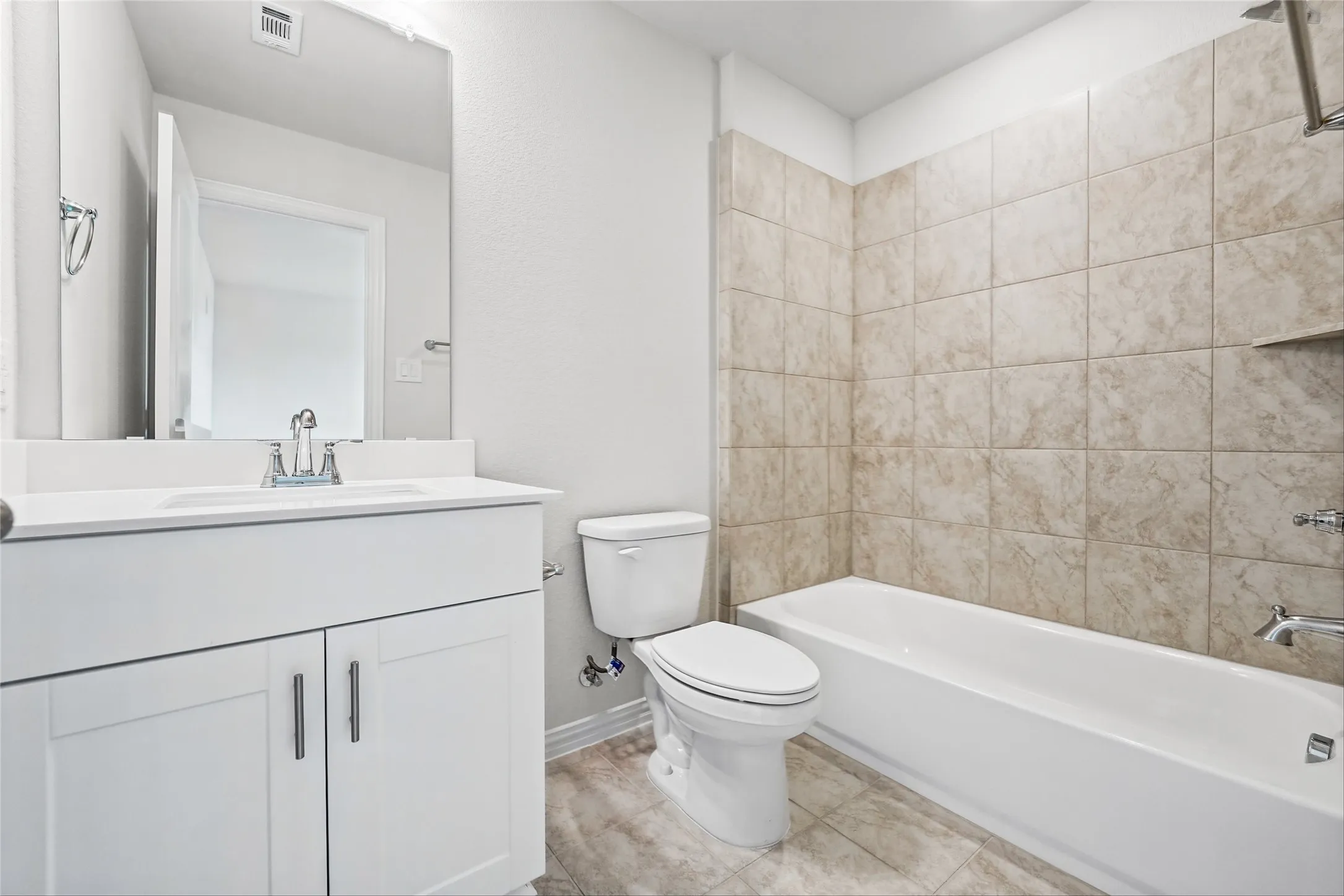 Bathroom featuring a white vanity with integrated sink, chrome faucet, and a large wall-mounted mirror