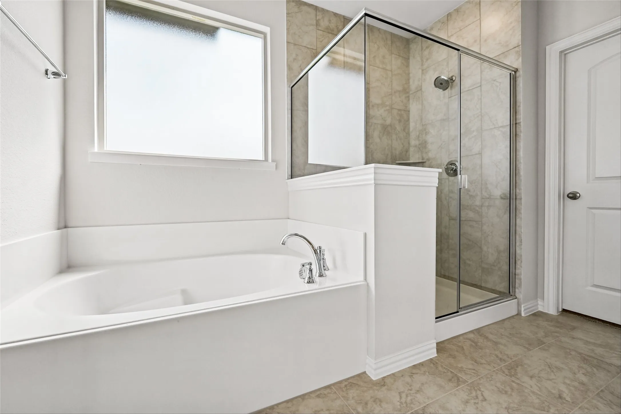 Built-in soaking tub with chrome fixtures, frosted glass window, separate glass-enclosed shower with tile surround, and tile flooring