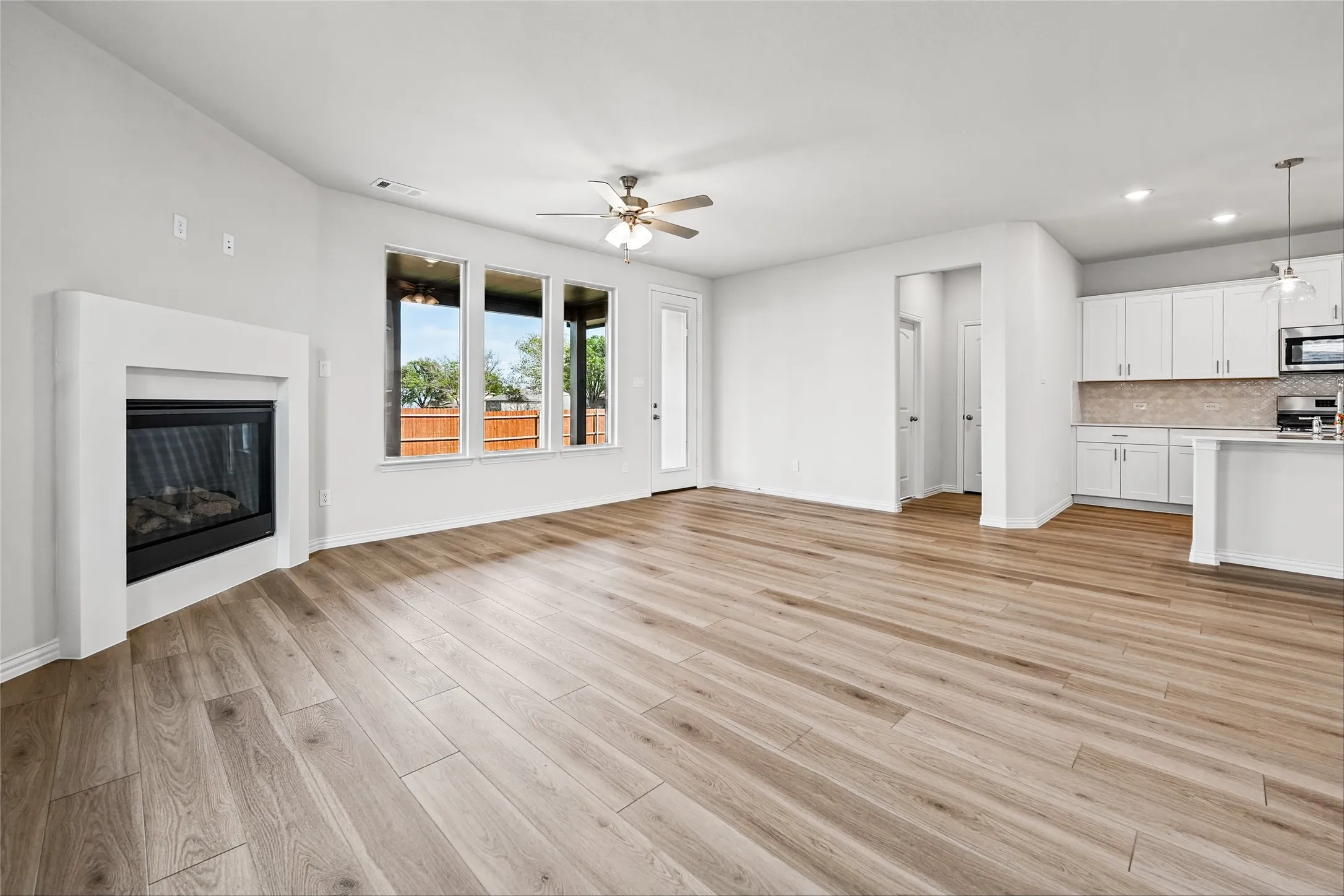 Wood-finish flooring throughout, multiple windows, built-in fireplace, ceiling fan, and recessed lighting