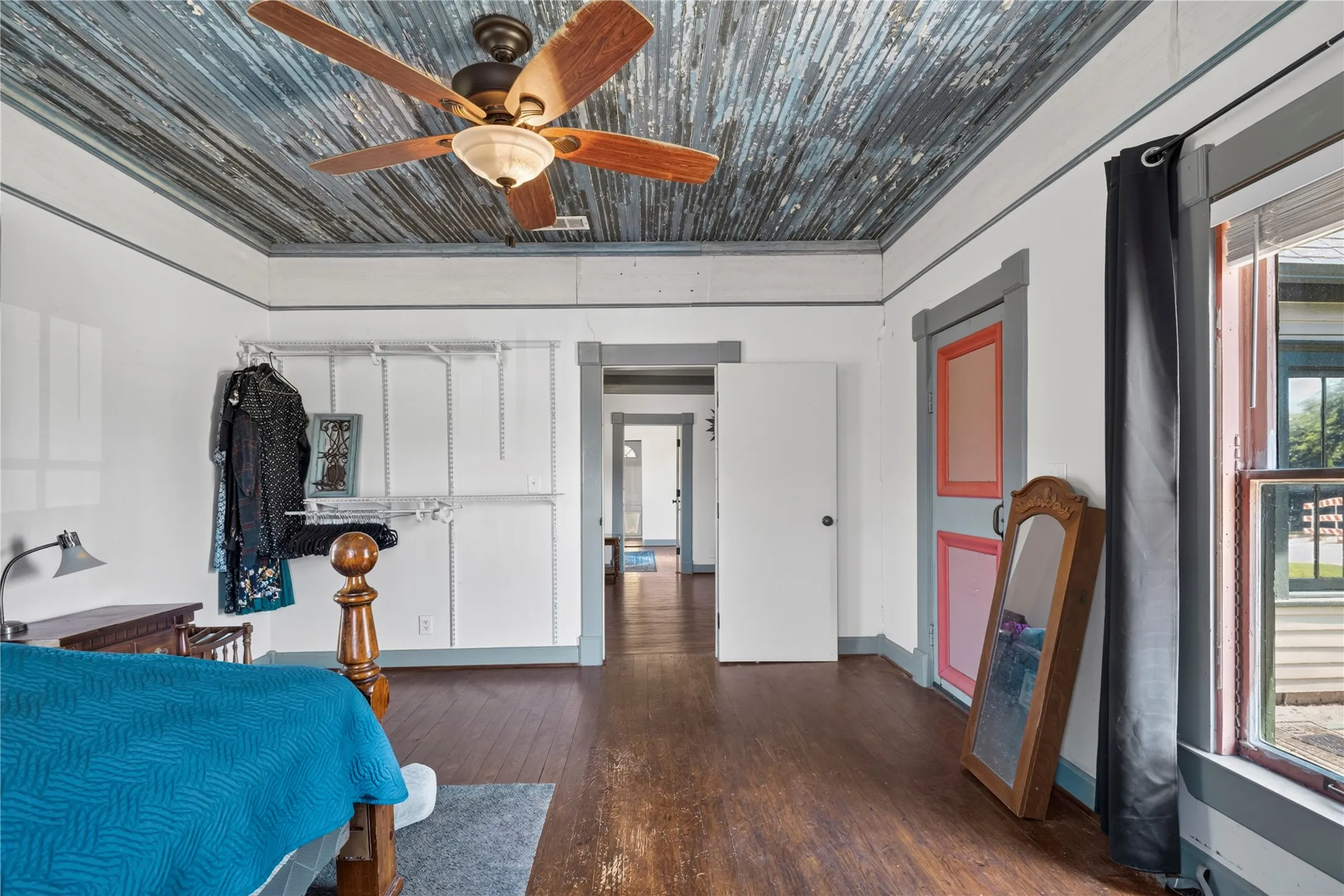 Interior room featuring a blue wood ceiling, dark wood-finish flooring, white walls, gray trim work, and a ceiling fan with integrated lighting