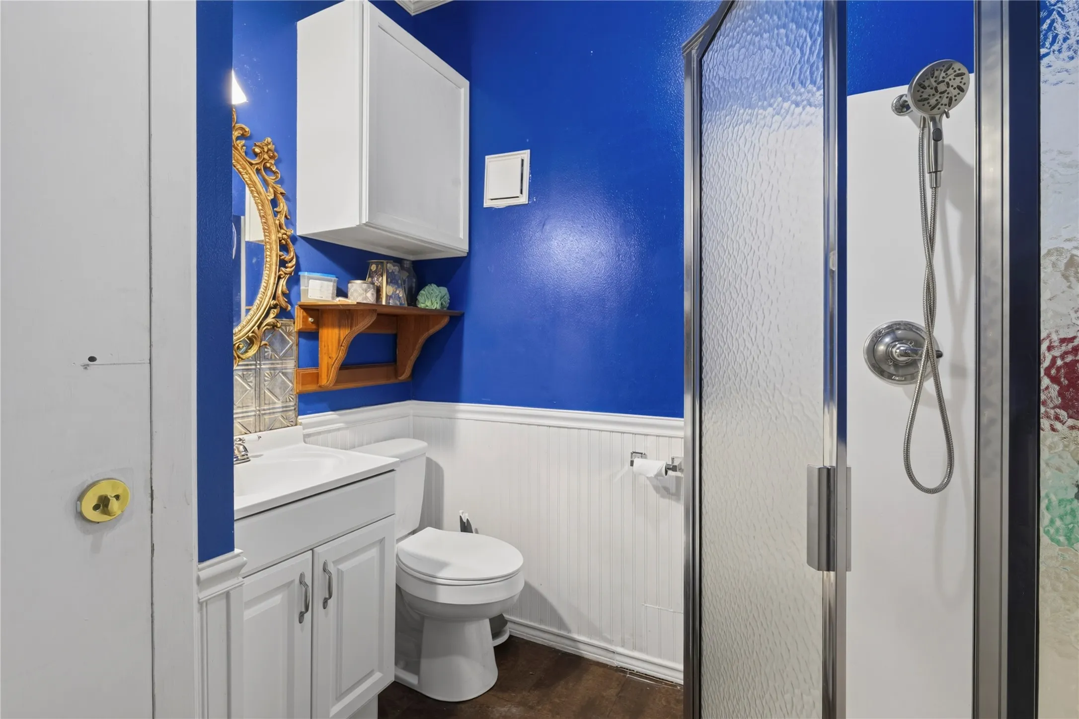Compact bathroom featuring a glass-enclosed shower with a handheld showerhead