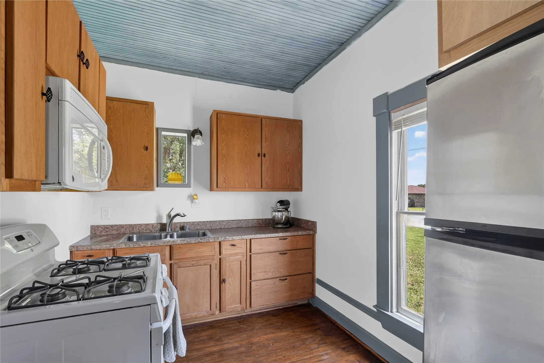 Kitchen featuring wood-finish flooring, wood cabinetry, laminate countertops, and a double basin sink