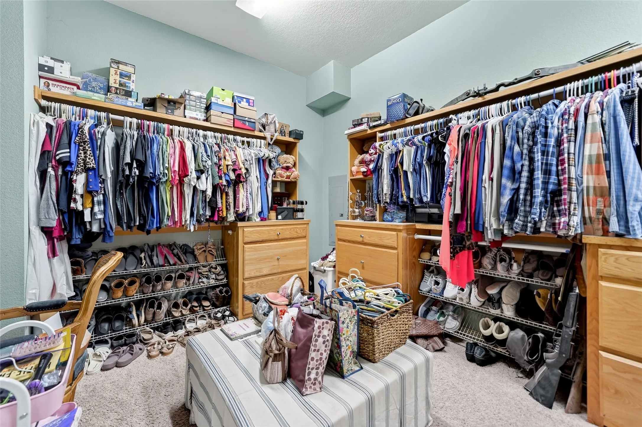 Spacious walk-in closet featuring extensive built-in shelving, hanging rods, and integrated drawer storage