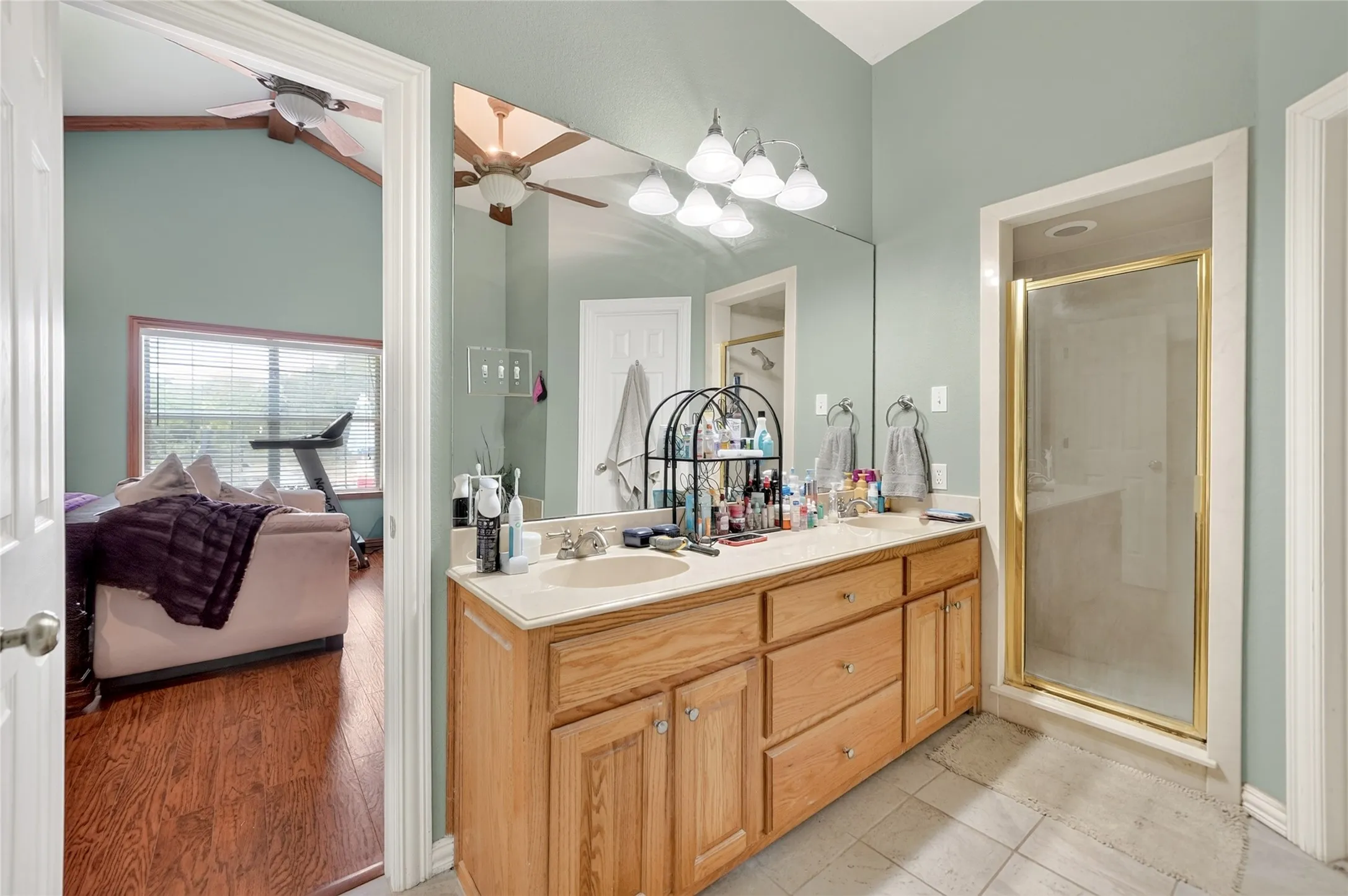 Double vanity with light wood cabinetry and integrated sinks, illuminated by a multi-bulb fixture