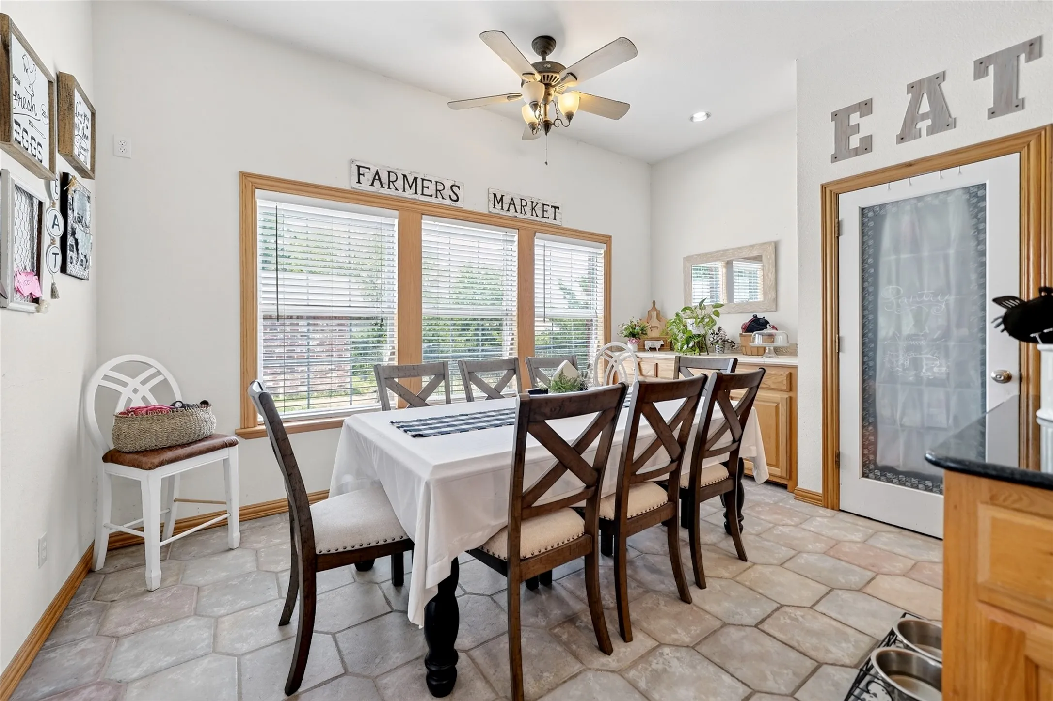 Dining area featuring hexagonal tile flooring, a multi-pane window with wood-finish trim, a ceiling fan with integrated lighting, and a built-in buffet with wood-finish cabinetry