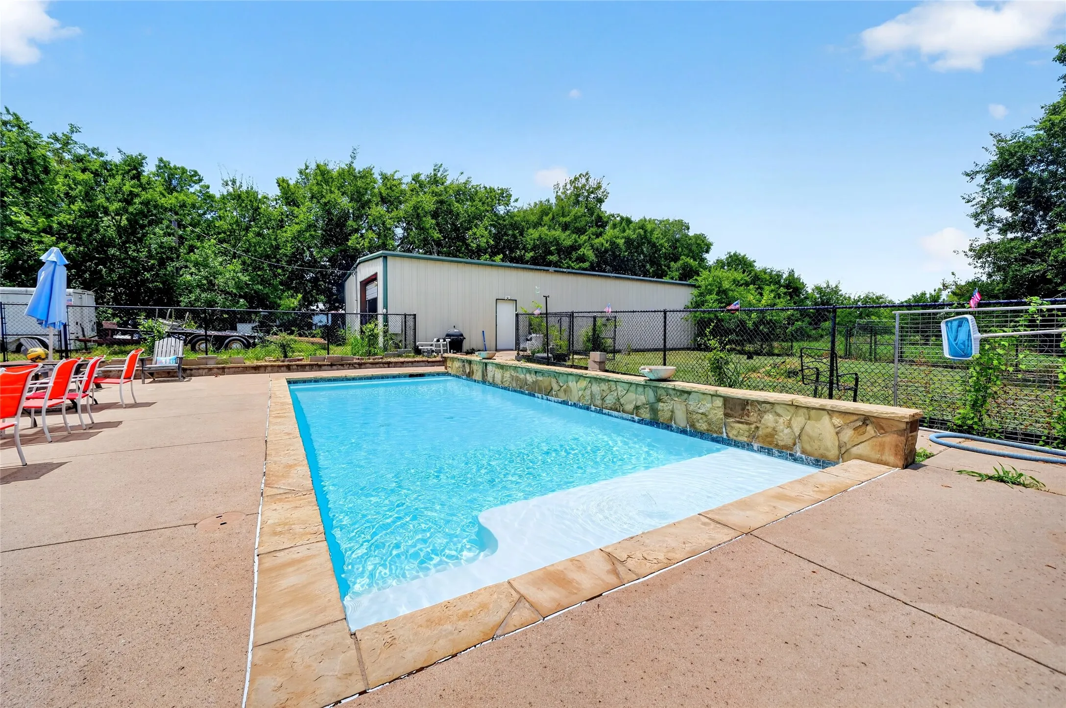 Rectangular in-ground pool featuring a stone-clad surround and concrete decking