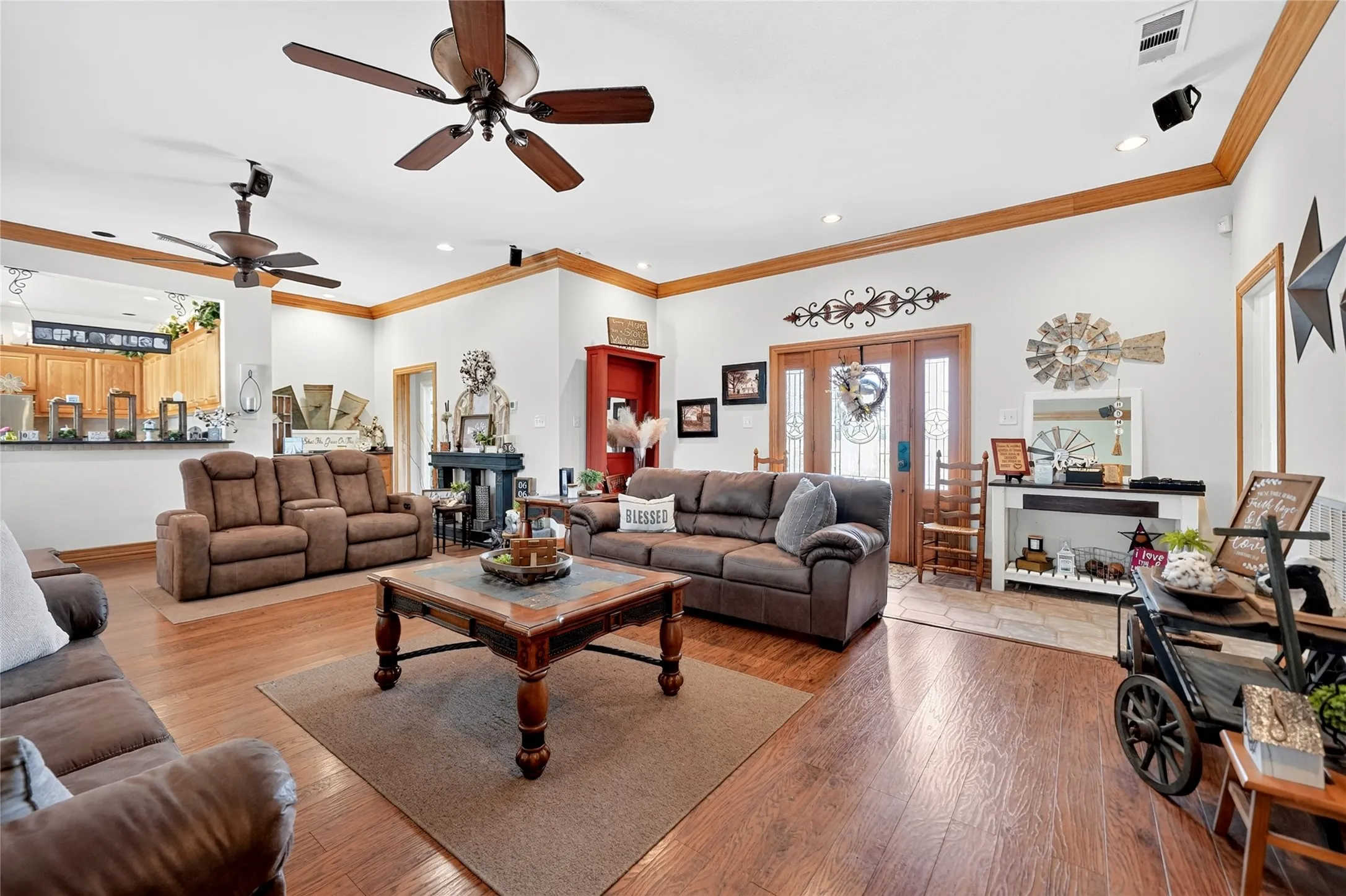 Spacious living area featuring wood-finish flooring, white walls, and a recessed ceiling with decorative wood trim