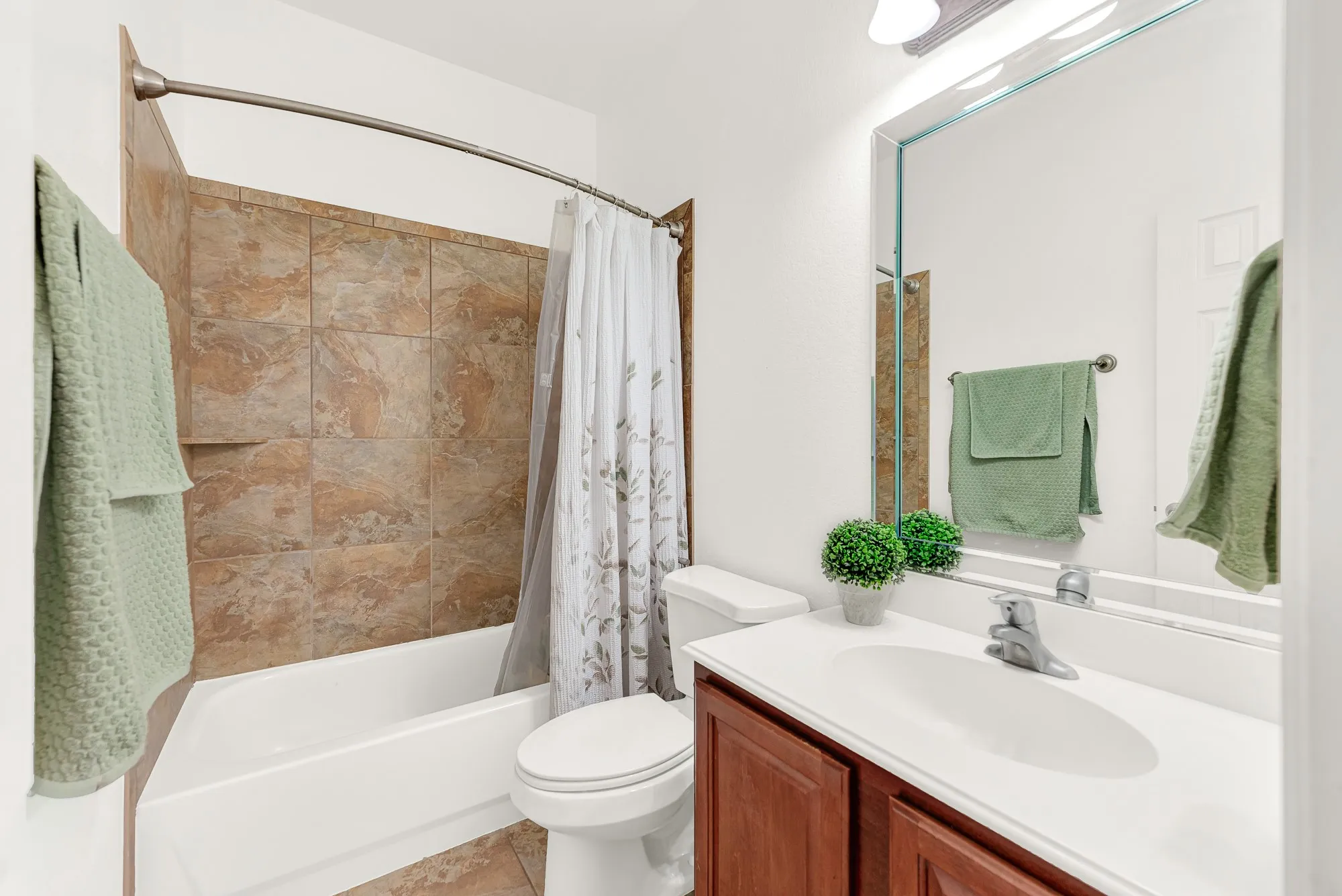 This full bathroom features timeless tile finishes and is conveniently located between the two downstairs secondary bedrooms for everyday ease. It provides a comfortable, private space for family members or overnight guests to feel right at home.