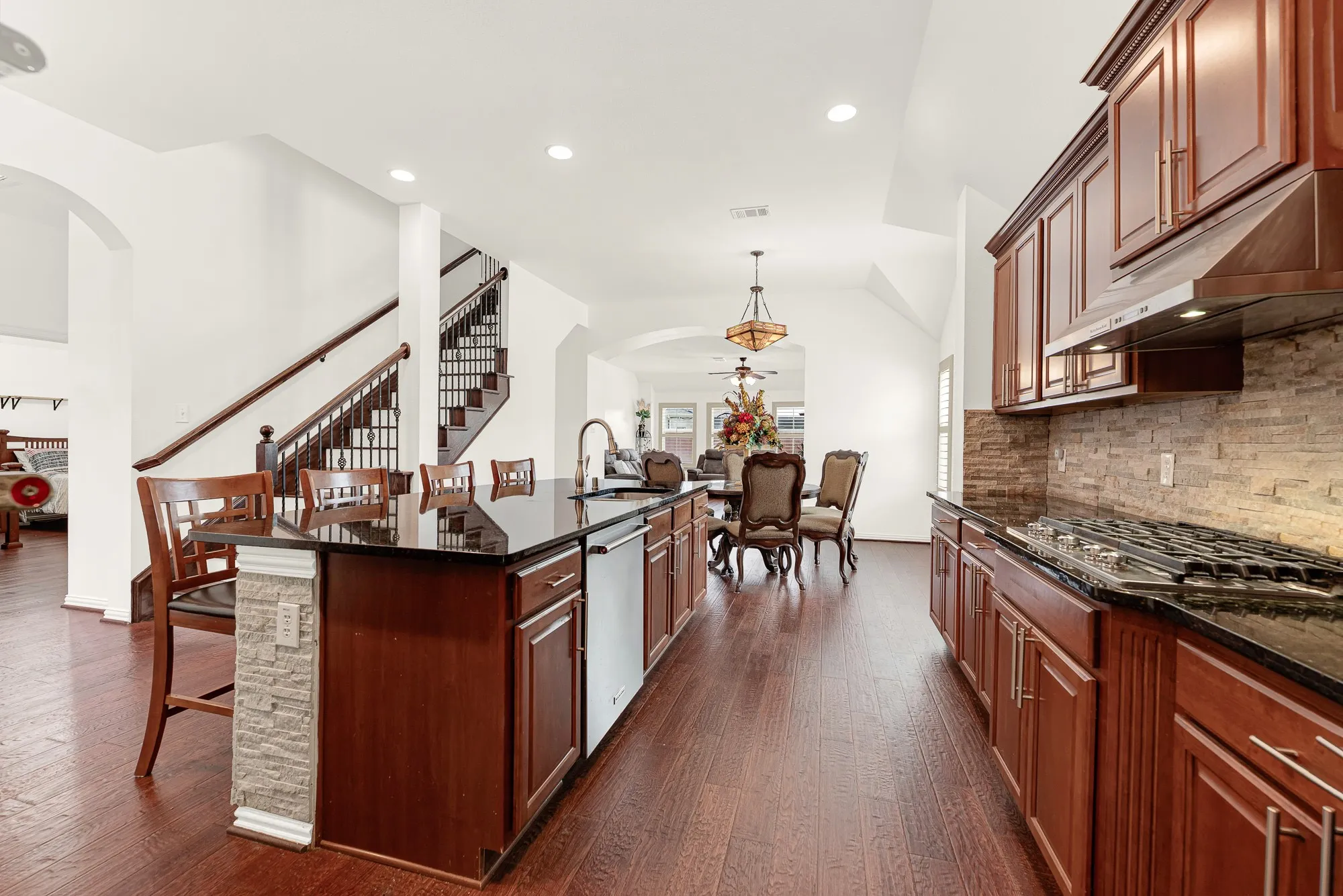 The oversized island anchors the room, offering generous prep space beneath high ceilings that make the entire area feel open and inviting. Friends naturally gather here over appetizers while dinner comes together just steps away.