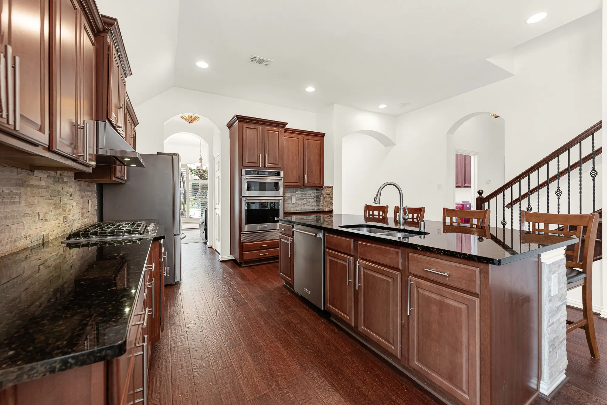 A gas cooktop, built-in wall oven, and stainless steel appliances pair with rich wood cabinetry and granite countertops to create a kitchen that's both refined and highly functional. Preparing meals feels effortless, whether it's a quiet dinner at home or a gathering with friends.