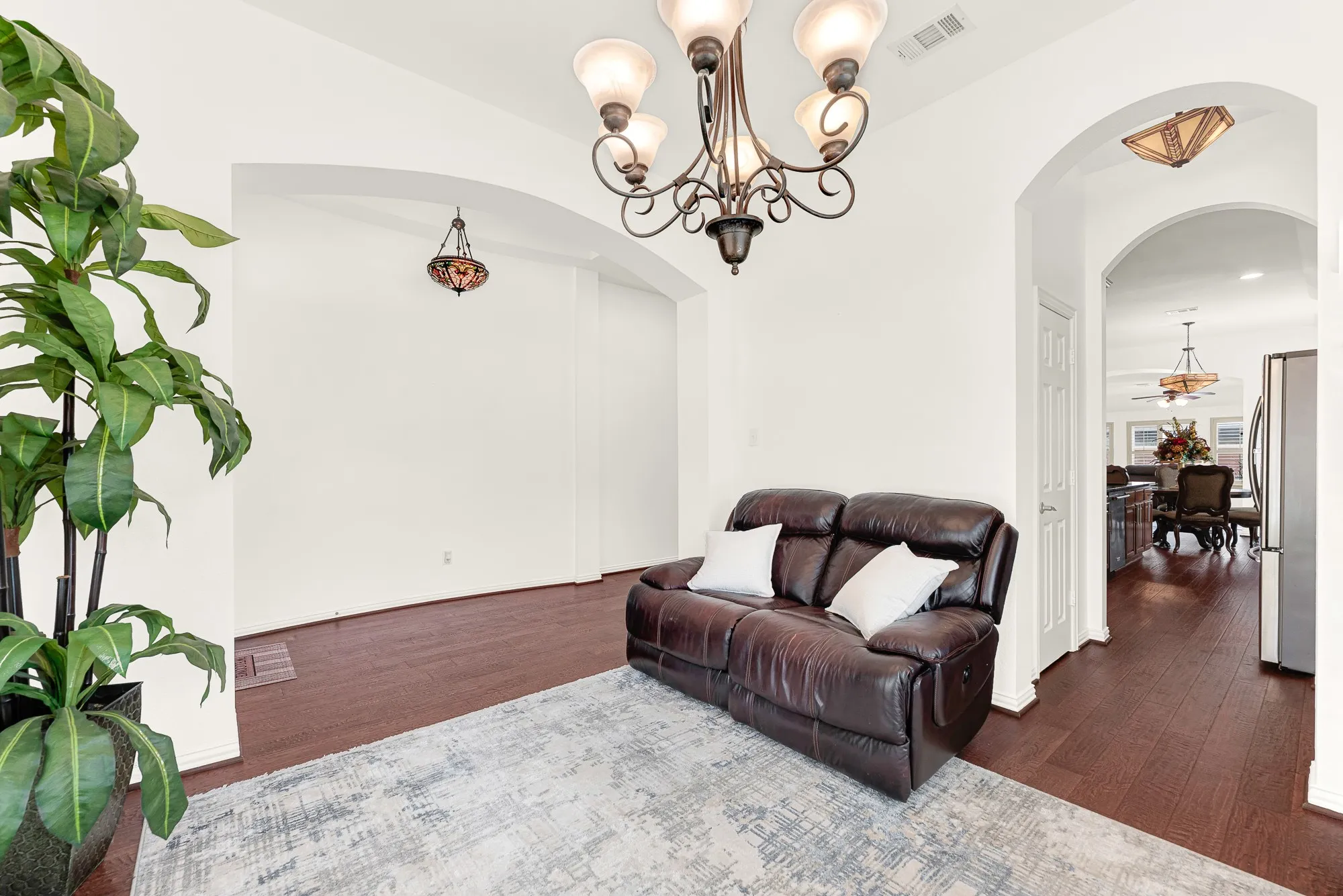 Wide arched openings create an effortless flow from the front of the home toward the kitchen and living spaces while defining this room as its own retreat. Whether you need a formal sitting area or a dedicated workspace, the layout adapts beautifully to your lifestyle.