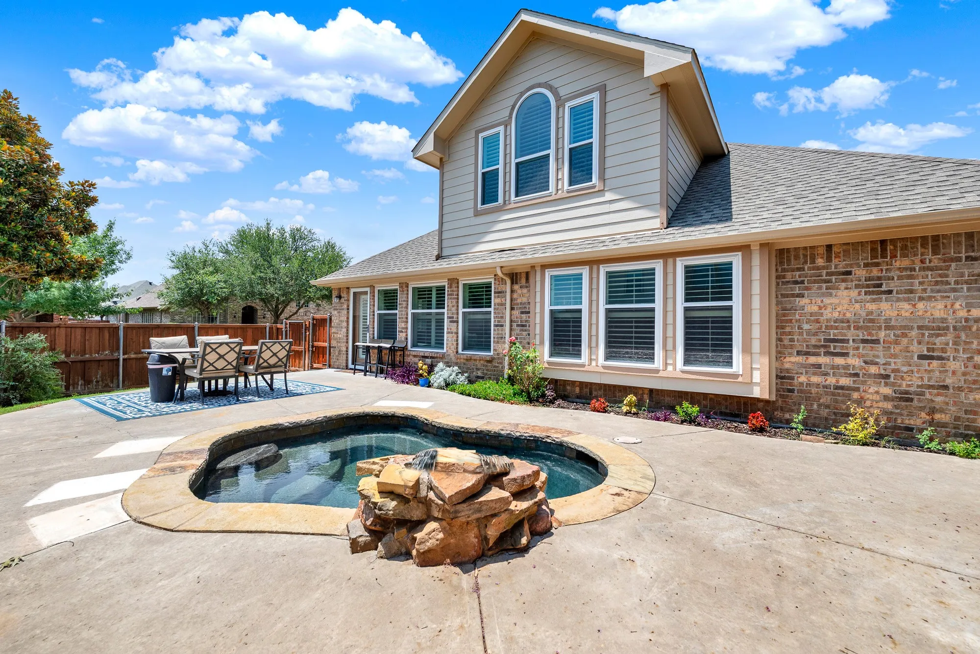 The bubbling spa and expansive patio create an inviting backyard retreat, while a wall of windows connects the home to the outdoor living space. Picture slow mornings with coffee on the patio or evenings unwinding by the water after hosting friends.