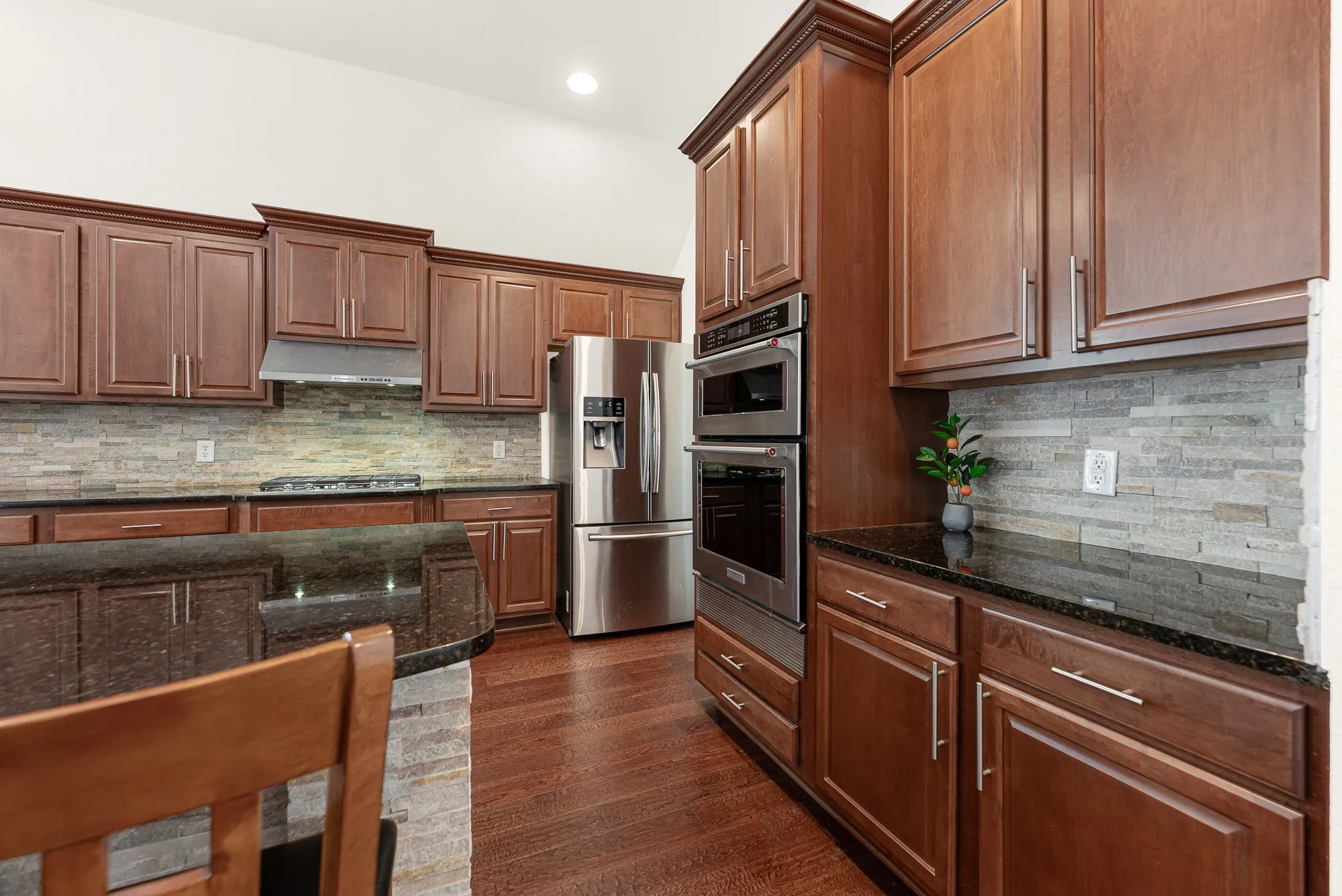 Expansive countertops, full-height cabinetry, and a textured stone backsplash provide exceptional workspace and storage, with the perfect nook for a dedicated coffee bar or beverage station. Start your mornings with everything organized and within reach before the day begins.