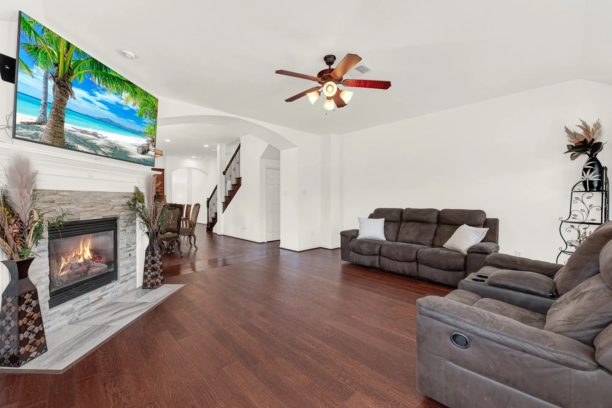 Rich wood flooring and the generous layout provide plenty of flexibility for multiple seating arrangements, making the space both comfortable and functional. Whether you're hosting game day, visiting with friends, or simply unwinding after work, there's room for everyone to spread out and relax.